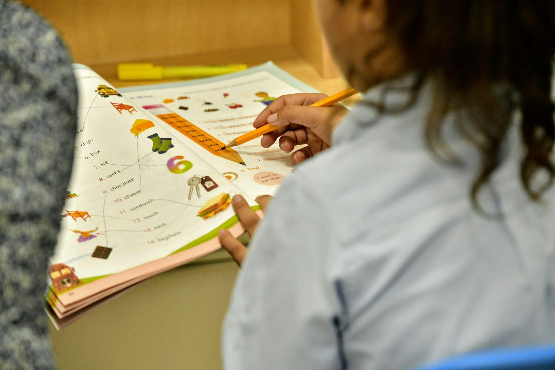 Student working through a workbook with a pencil