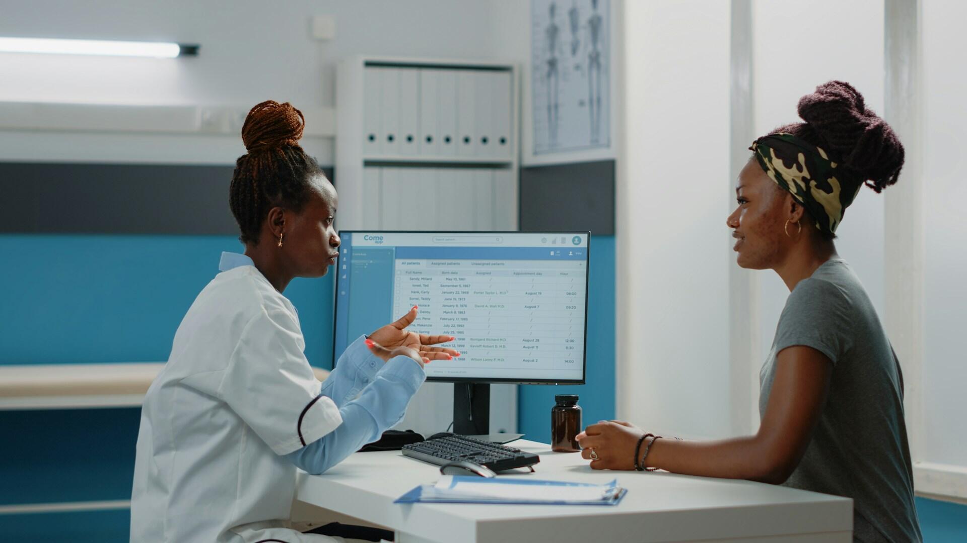 A nurse discussing information on a computer screen with a patient.