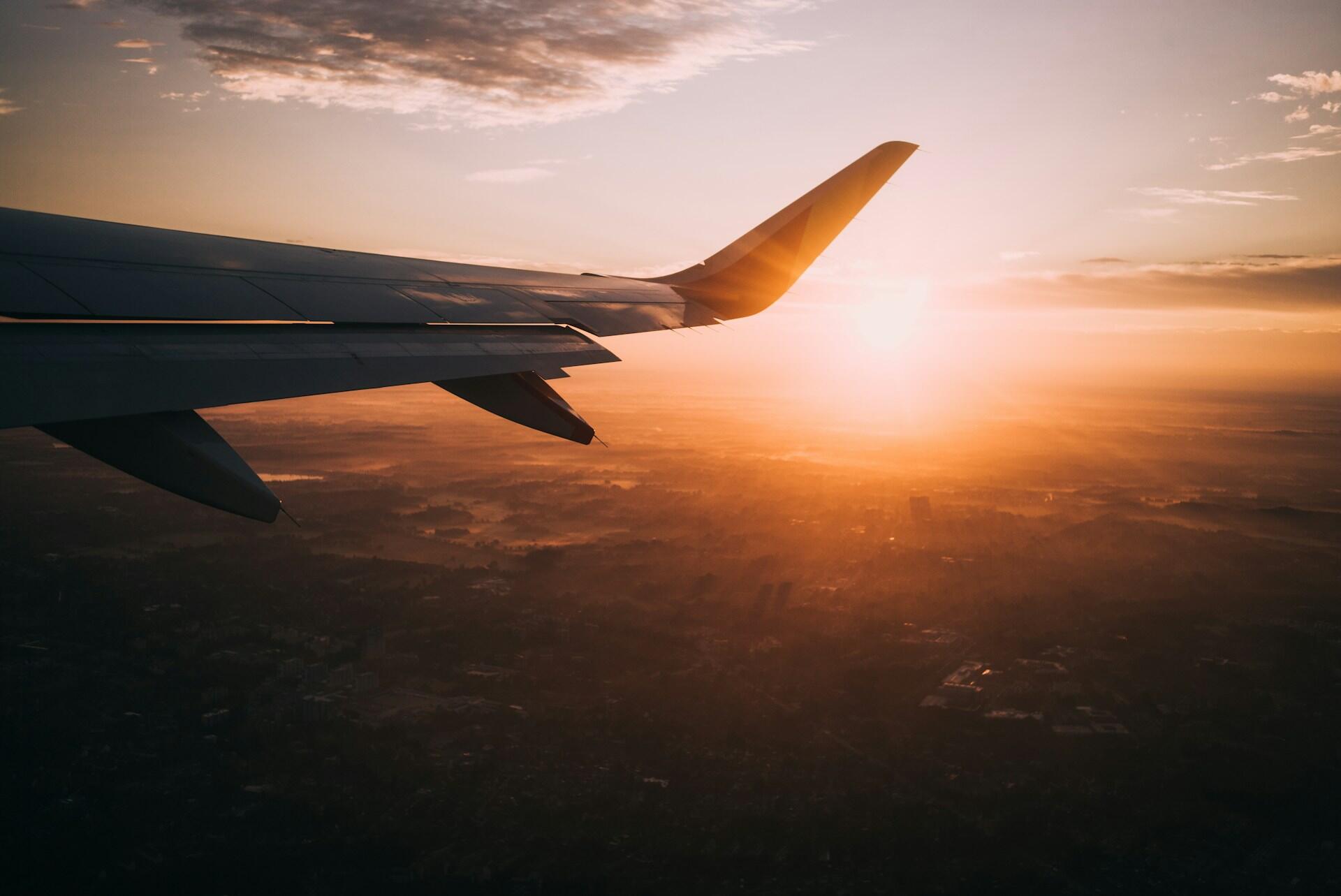 A view of a plane wing over a sunset or sunrise.