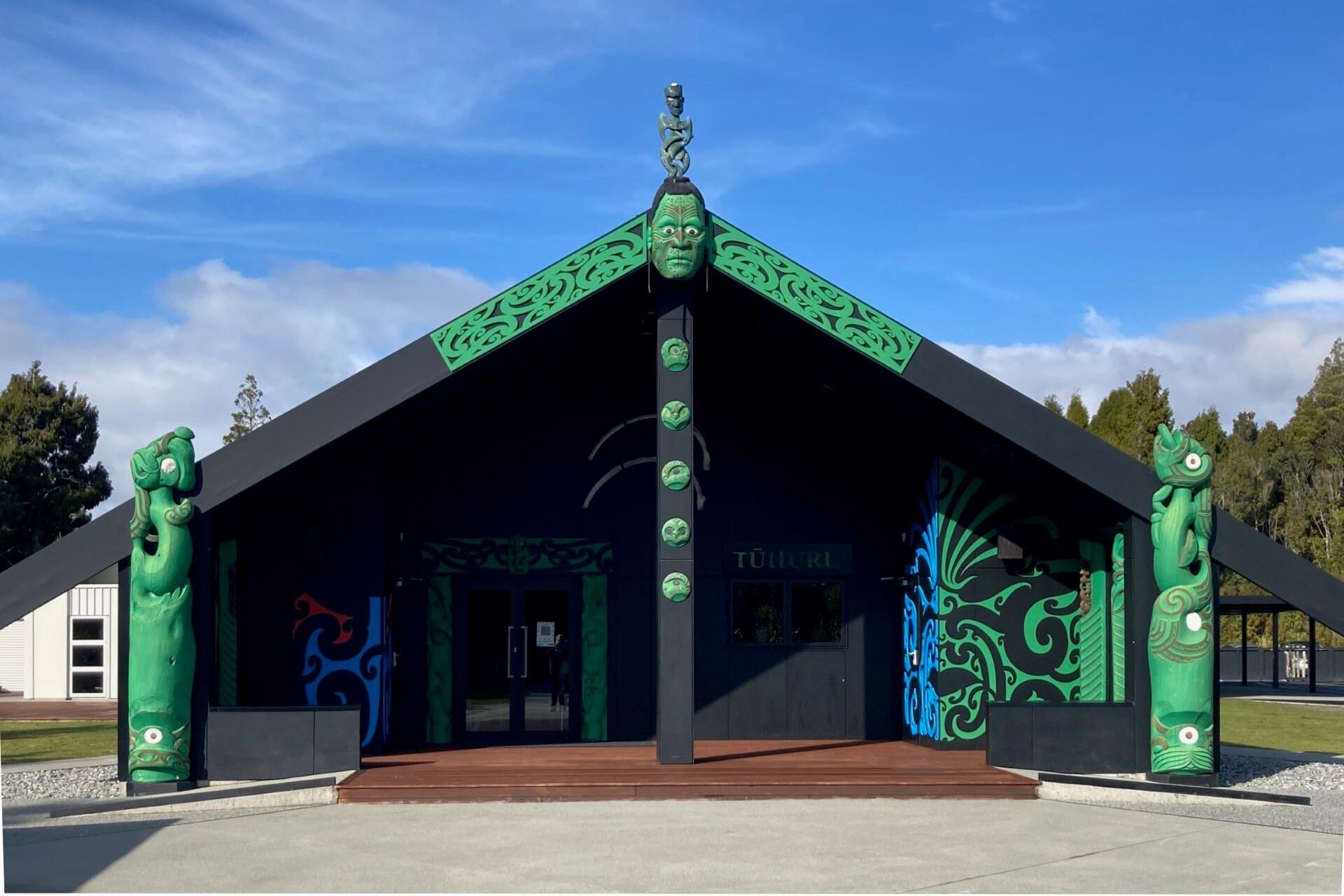 Entrance of Arahura Marae in Tūhuru with carved posts and Māori decorative patterns.