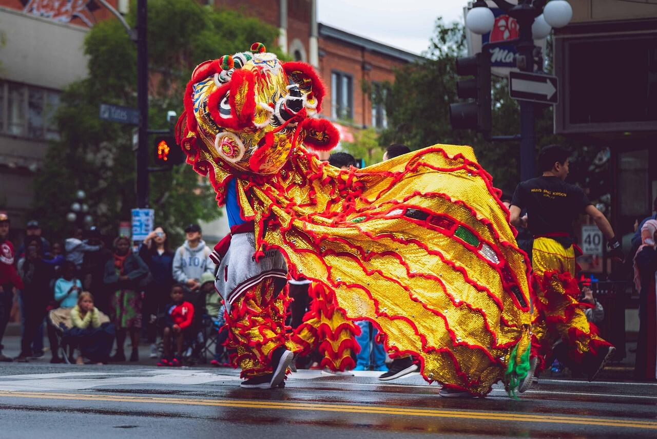 Man doing a dragon dance on a street as part of a parade.