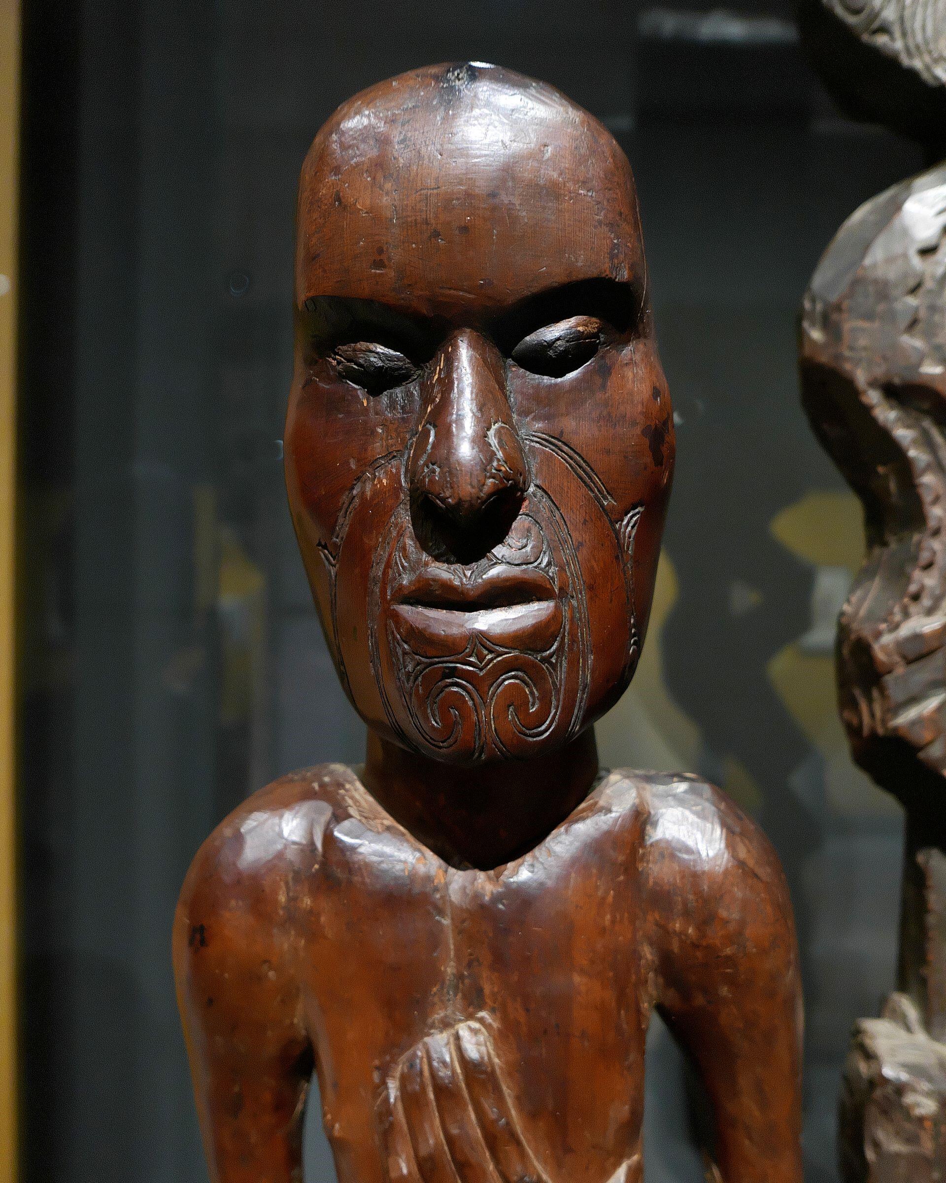 Traditional Māori wooden carving of an ancestor figure with detailed facial patterns