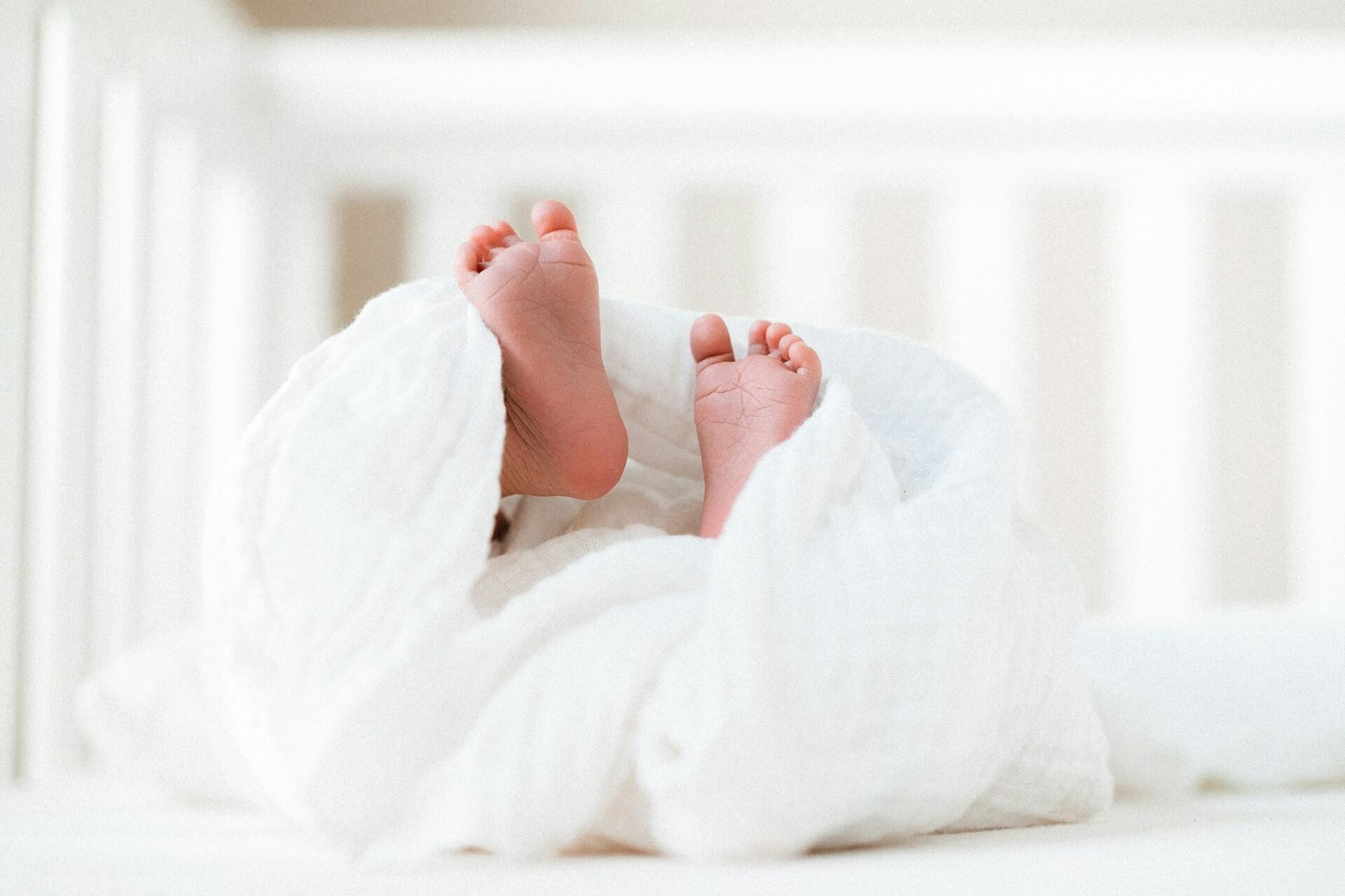 baby feet sticking out of white blanket