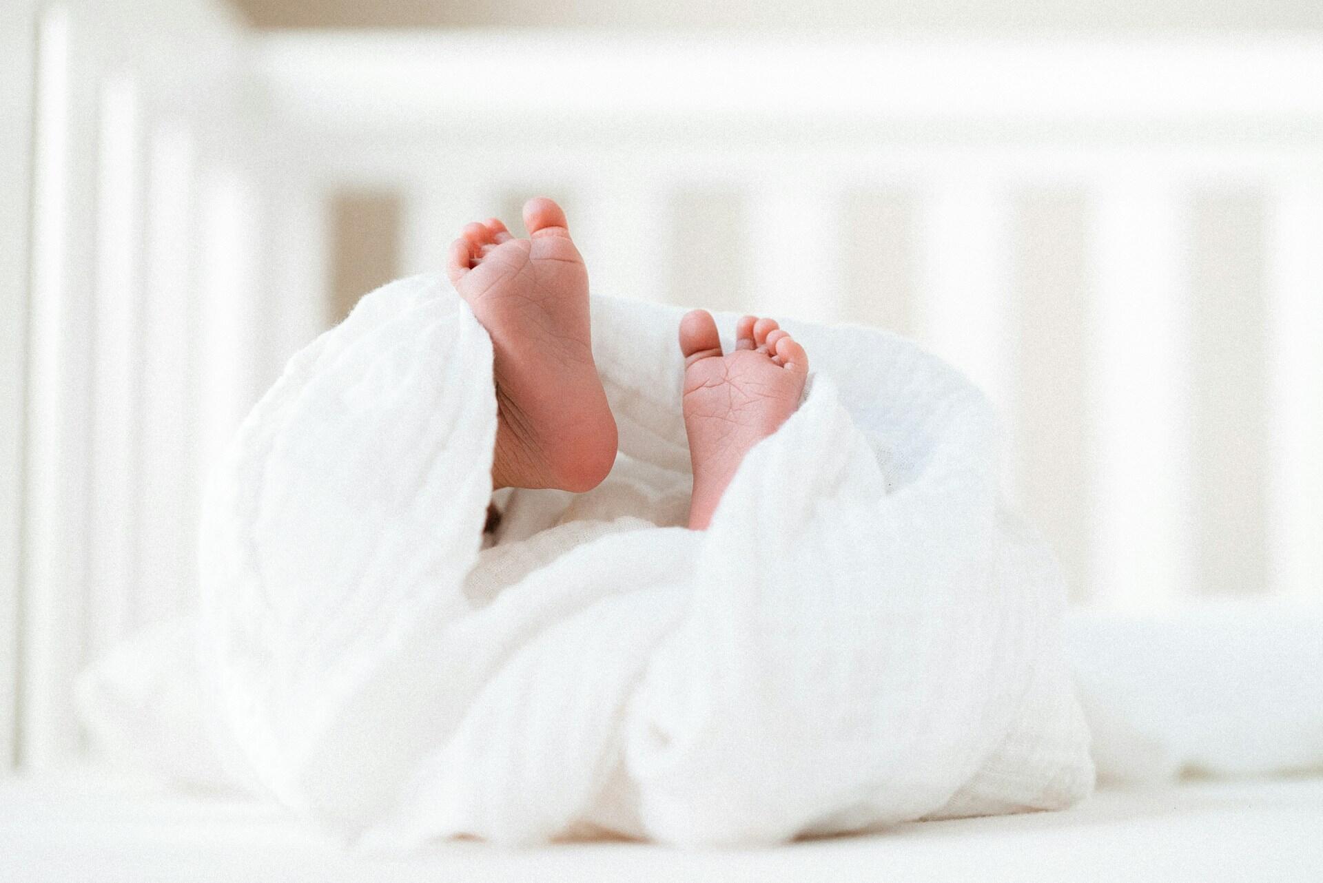 Baby feet sticking out of white blanket