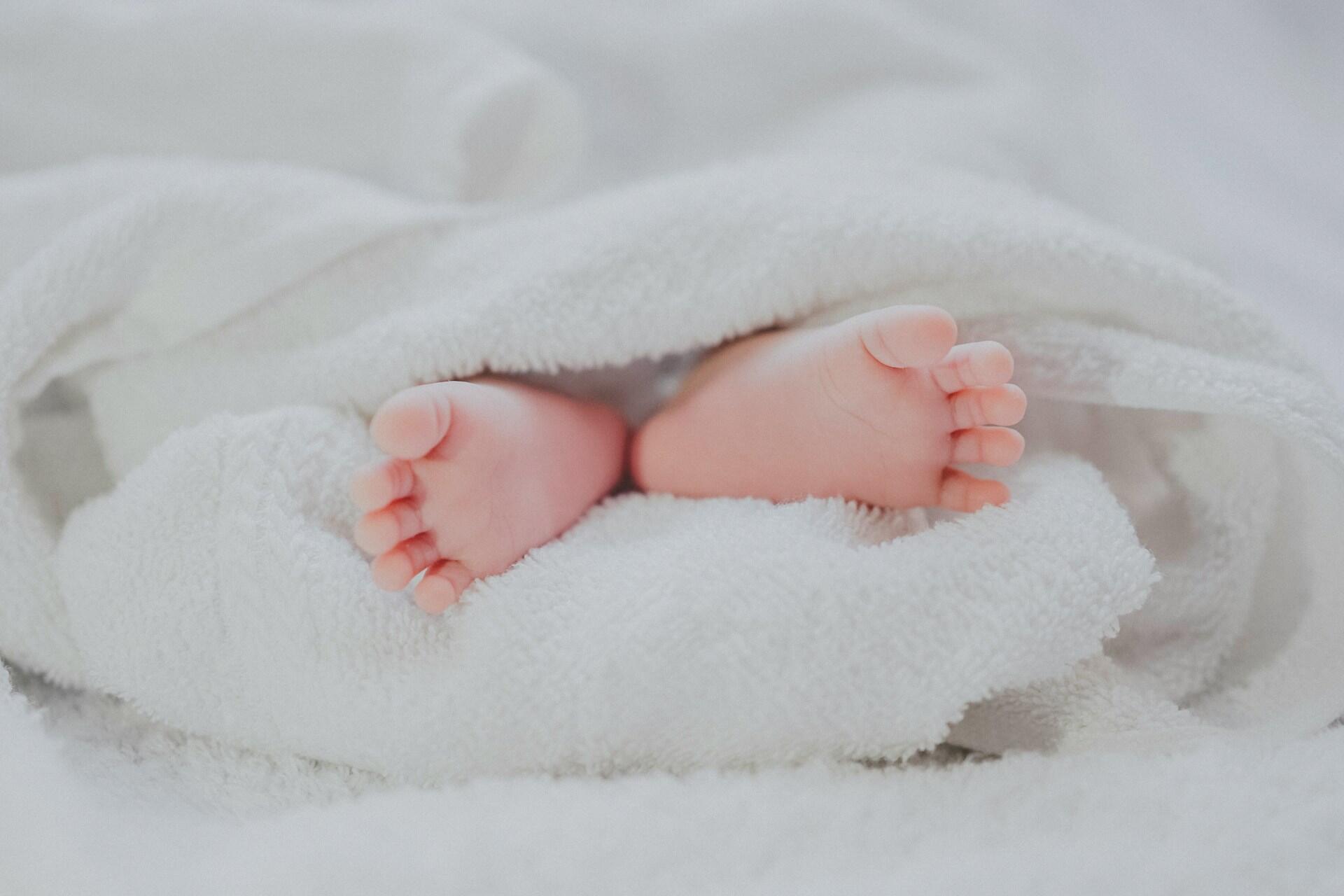 Baby feet wrapped in soft white blanket