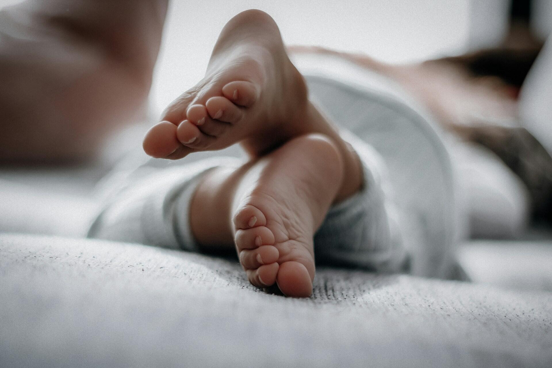 Baby feet resting on bed close up