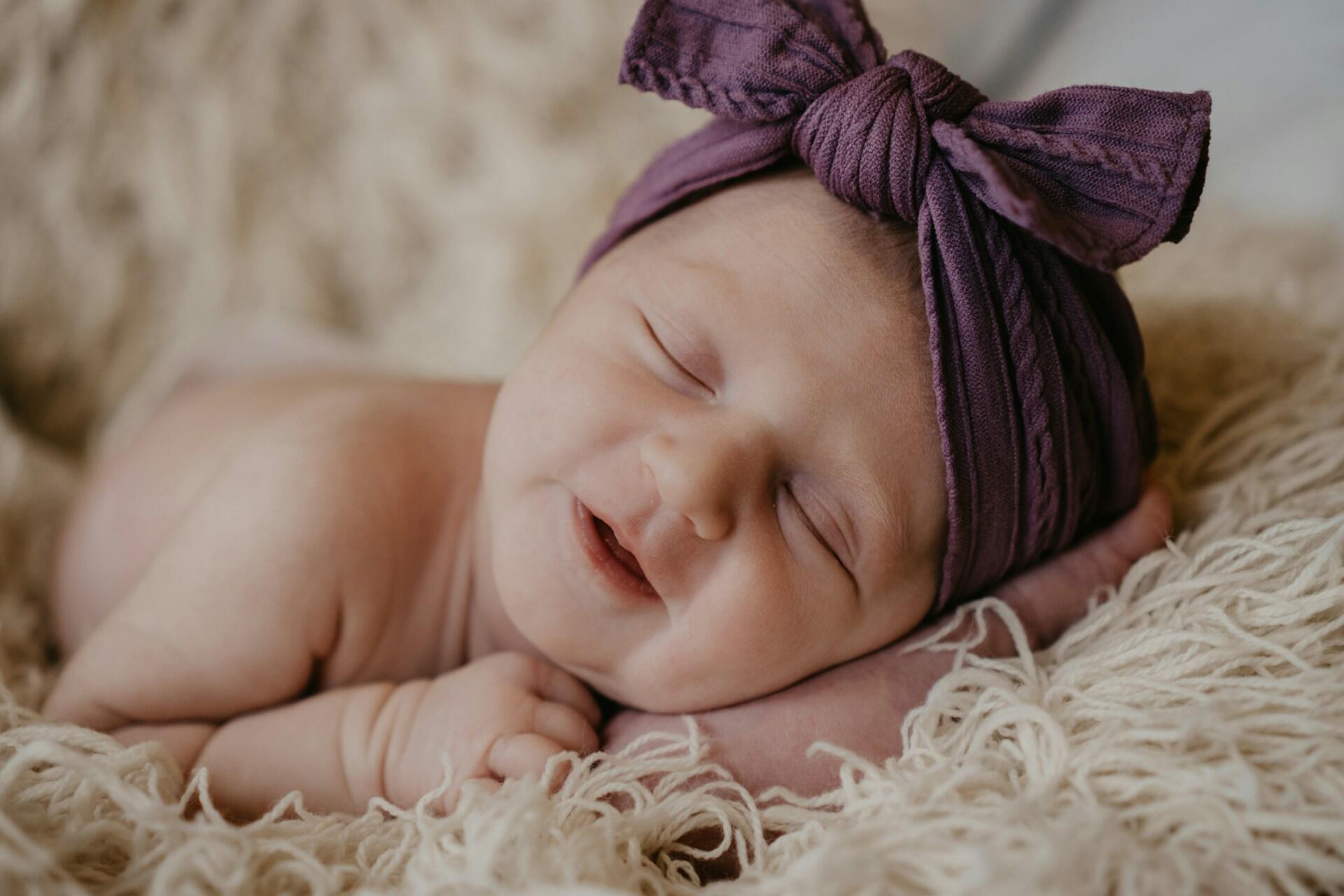 Sleeping baby wearing purple headband bow