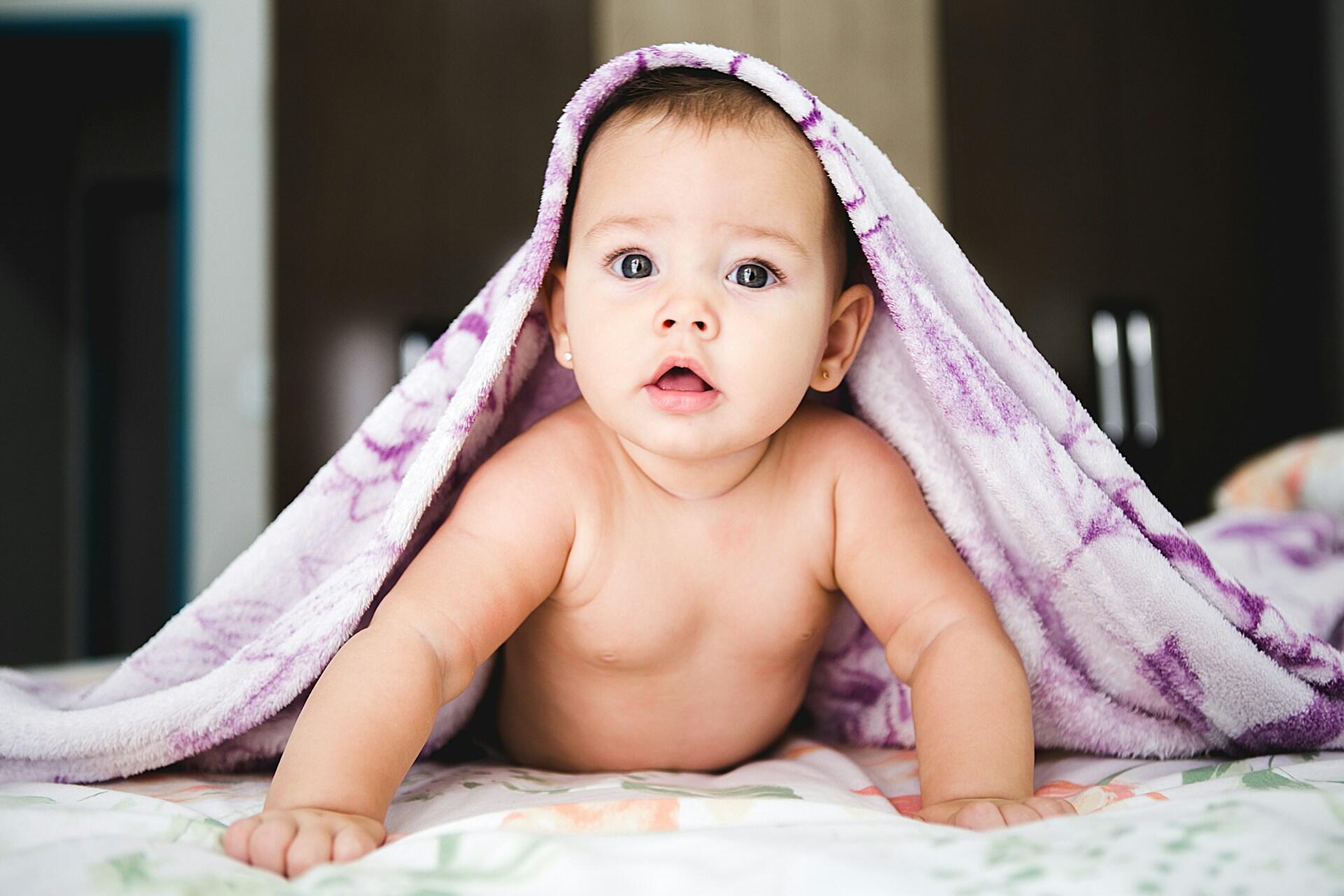 Baby under towel looking at camera