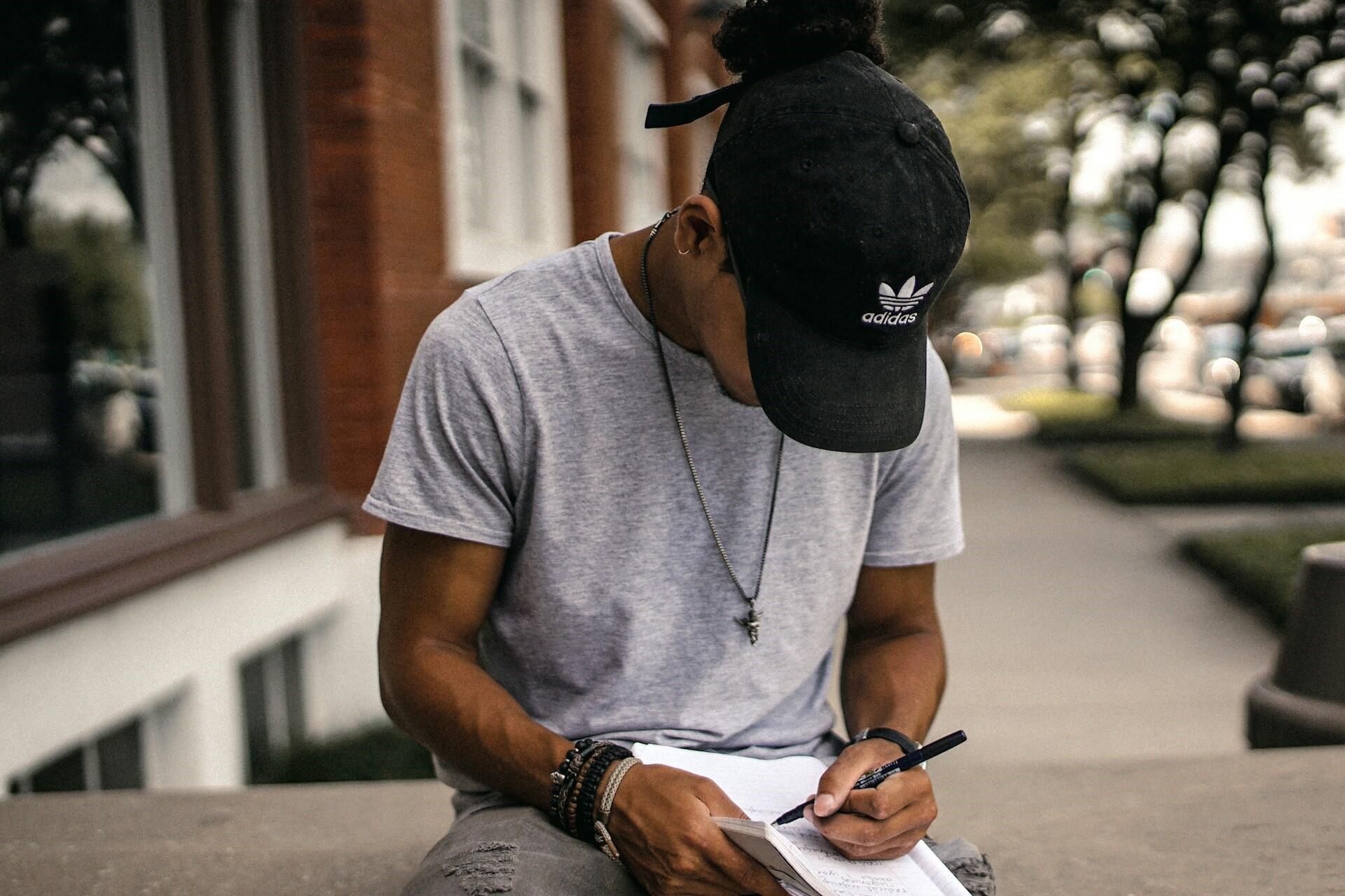 student sitting outside writing in a notebook