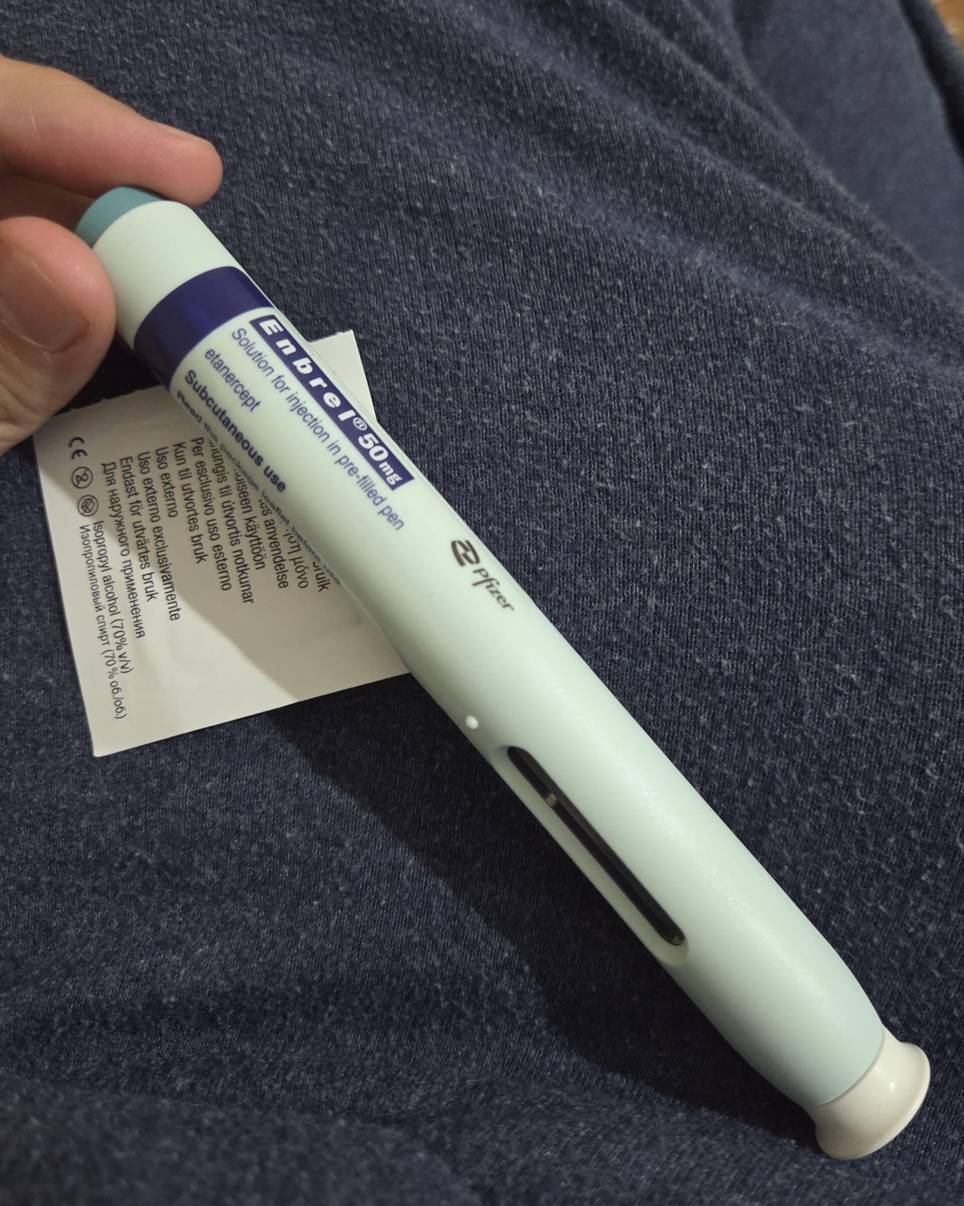 Hand holding an auto-injector pen device with label visible