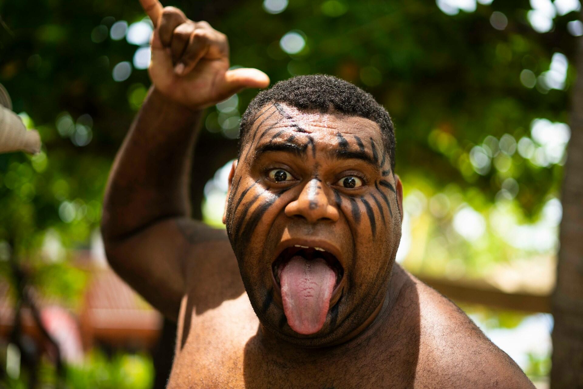 man with face paint performing haka expression with tongue out