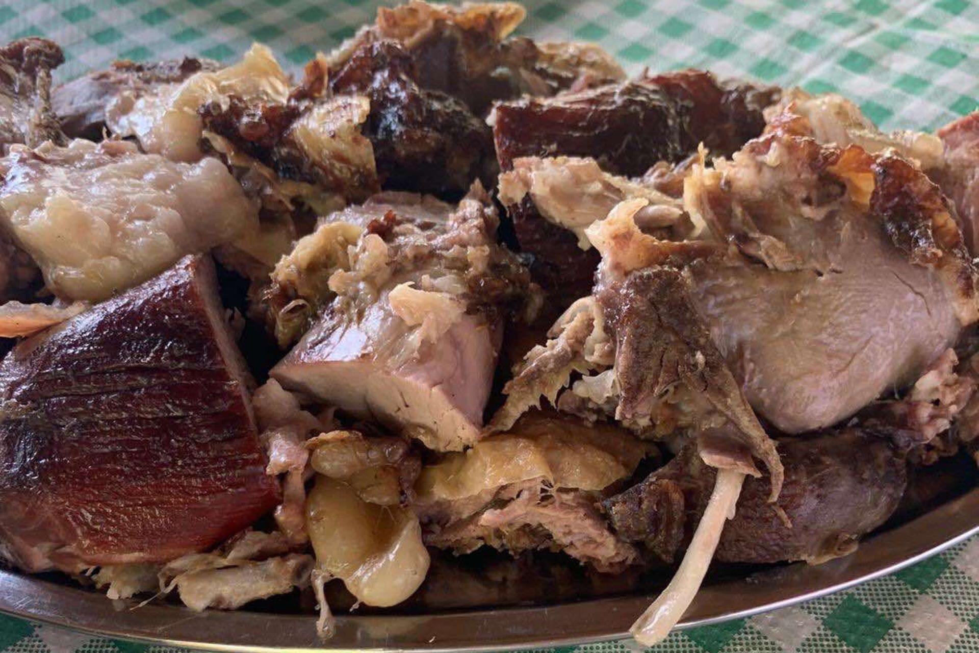 Close-up of roasted lamb pieces with browned skin and visible bone on a serving plate