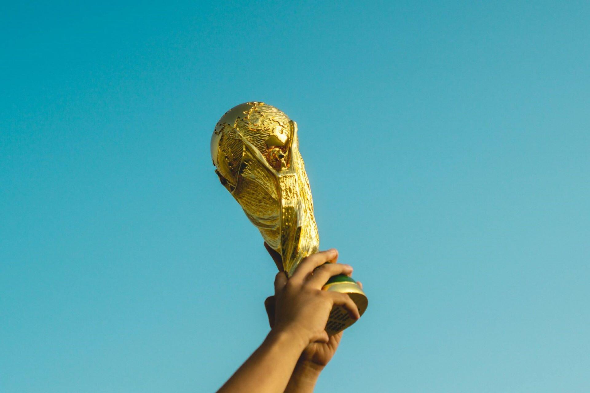 FIFA World Cup trophy held up against a blue sky