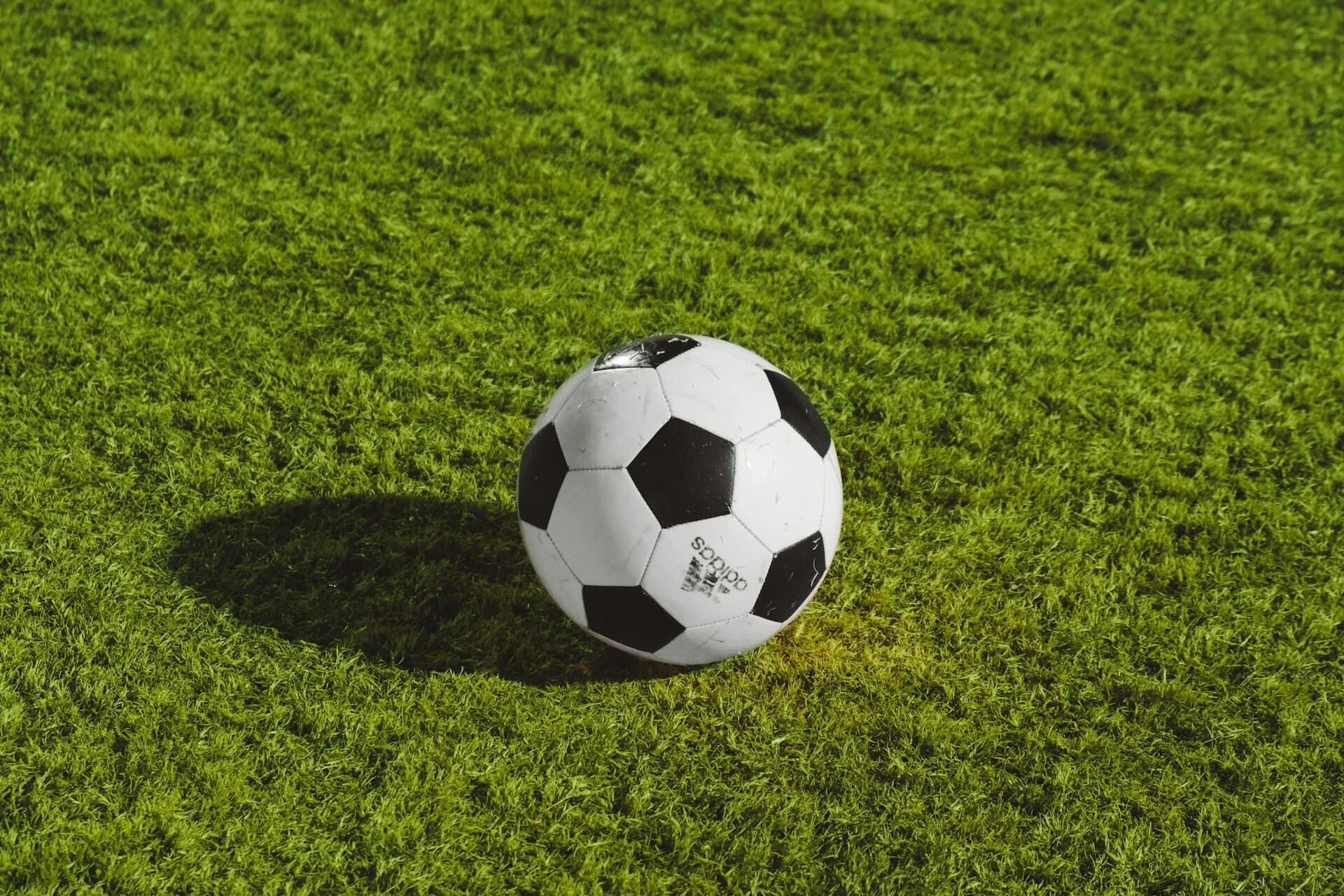 Black and white football on green grass