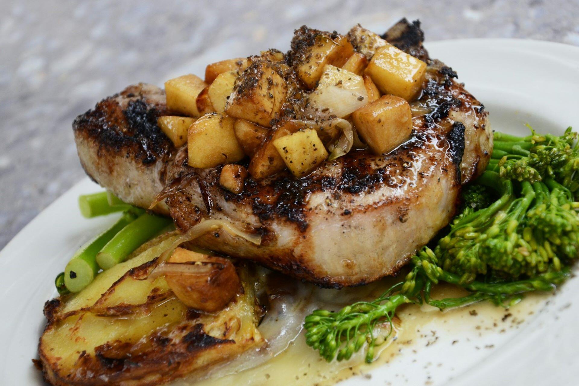 A plated meal with meat, potatoes, sauce and green vegetables