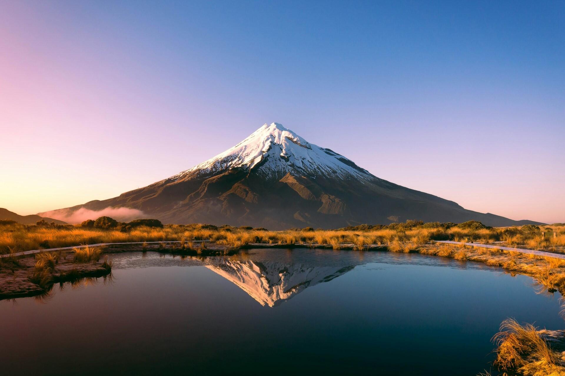 Snow-capped mountain reflected in still water at sunrise