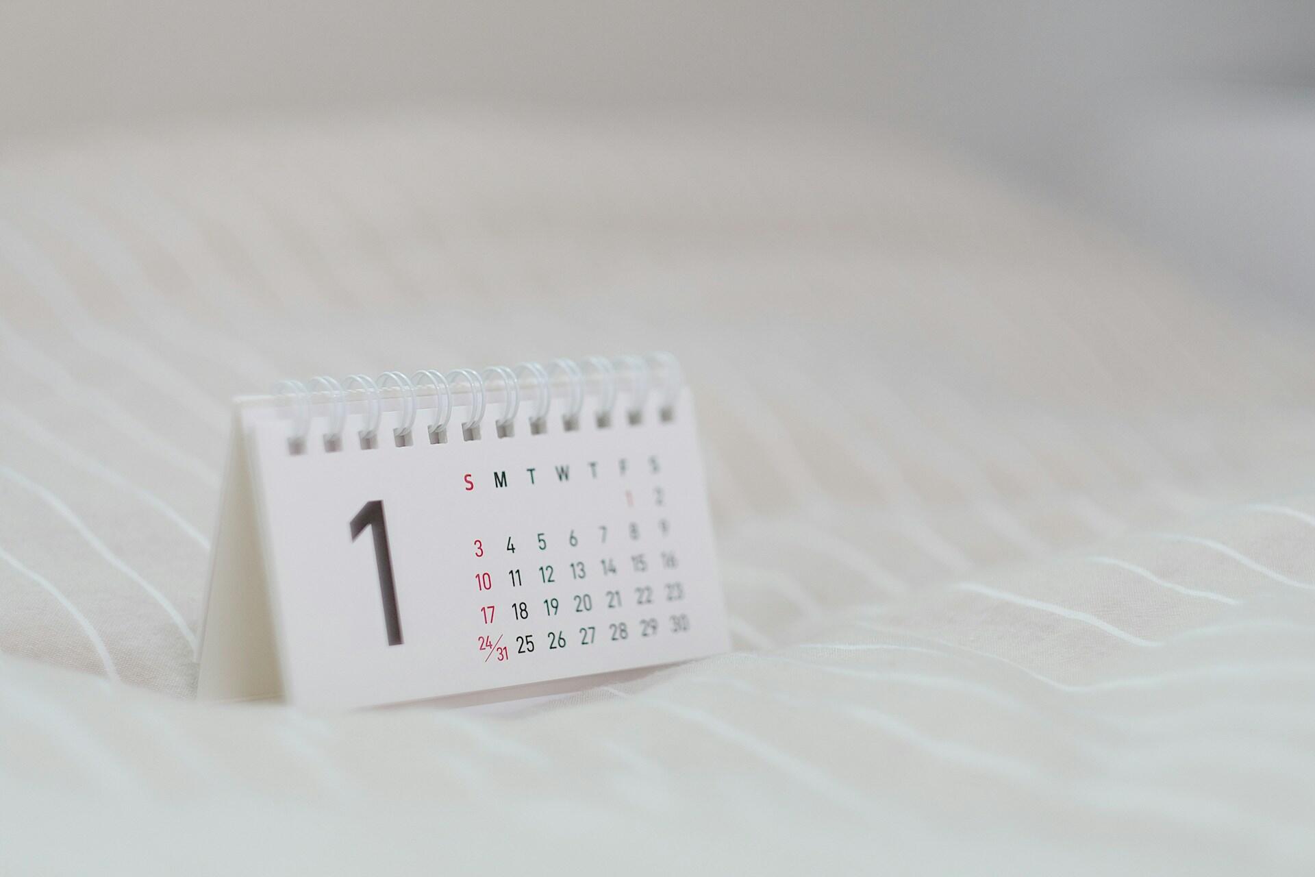 Small white desk calendar showing the number one on a white fabric surface