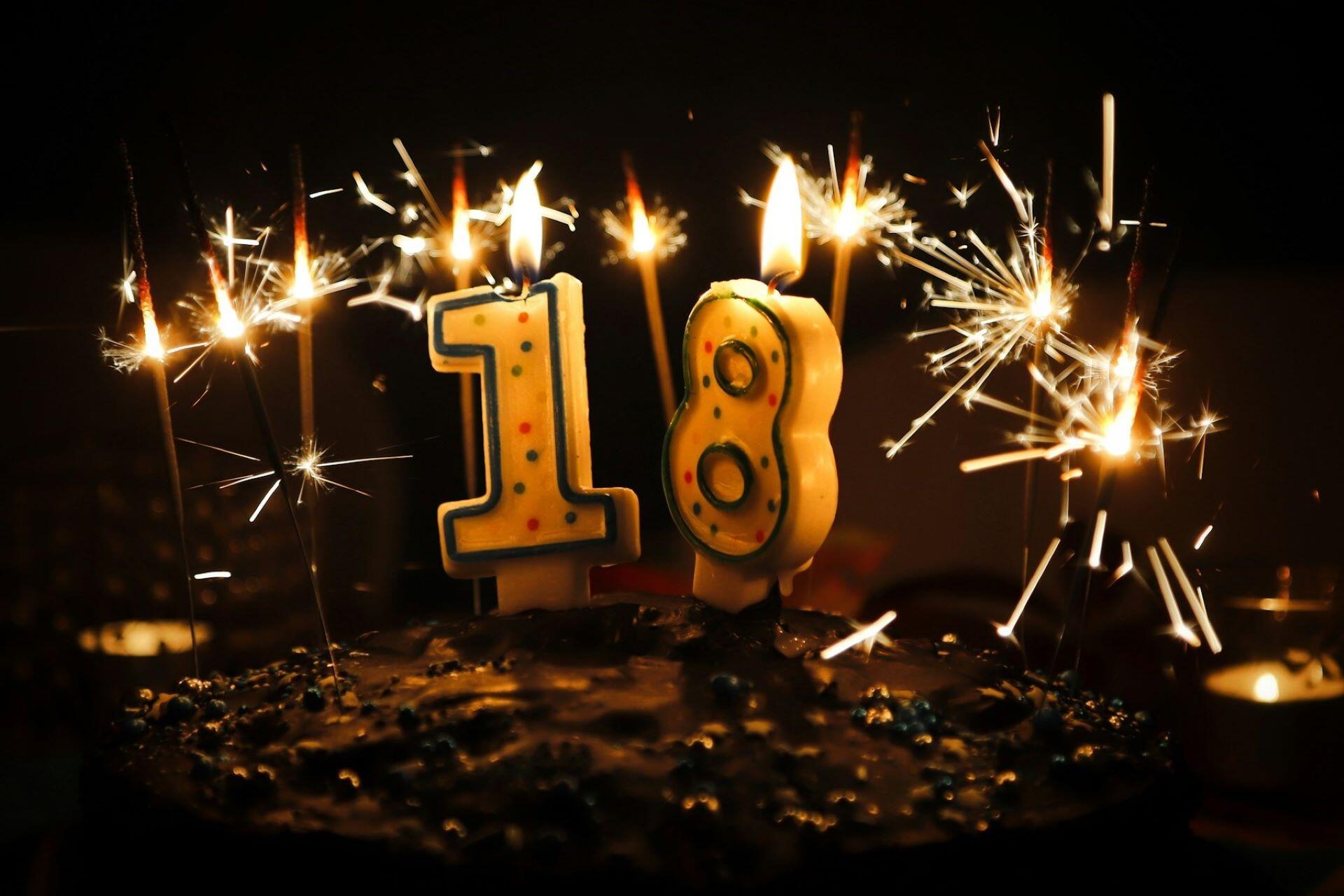 Number 18 candles burning among lit sparklers