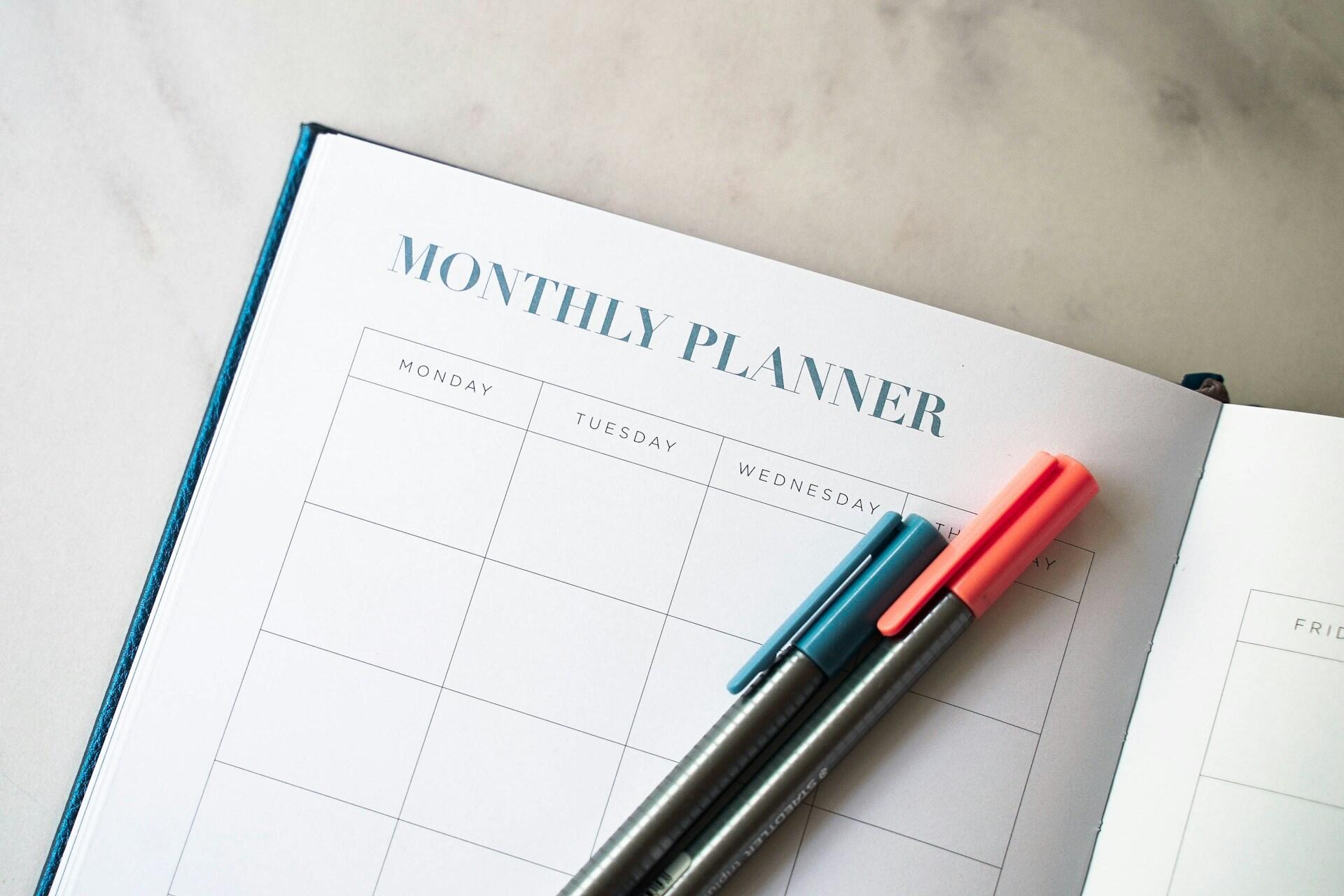 Open monthly planner with blue and pink pens