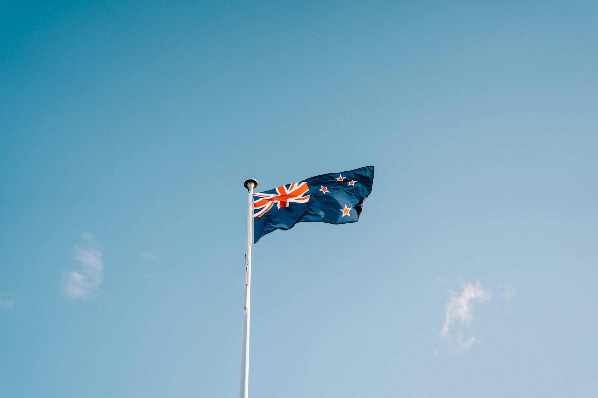 New Zealand flag flying on a pole beneath a blue sky