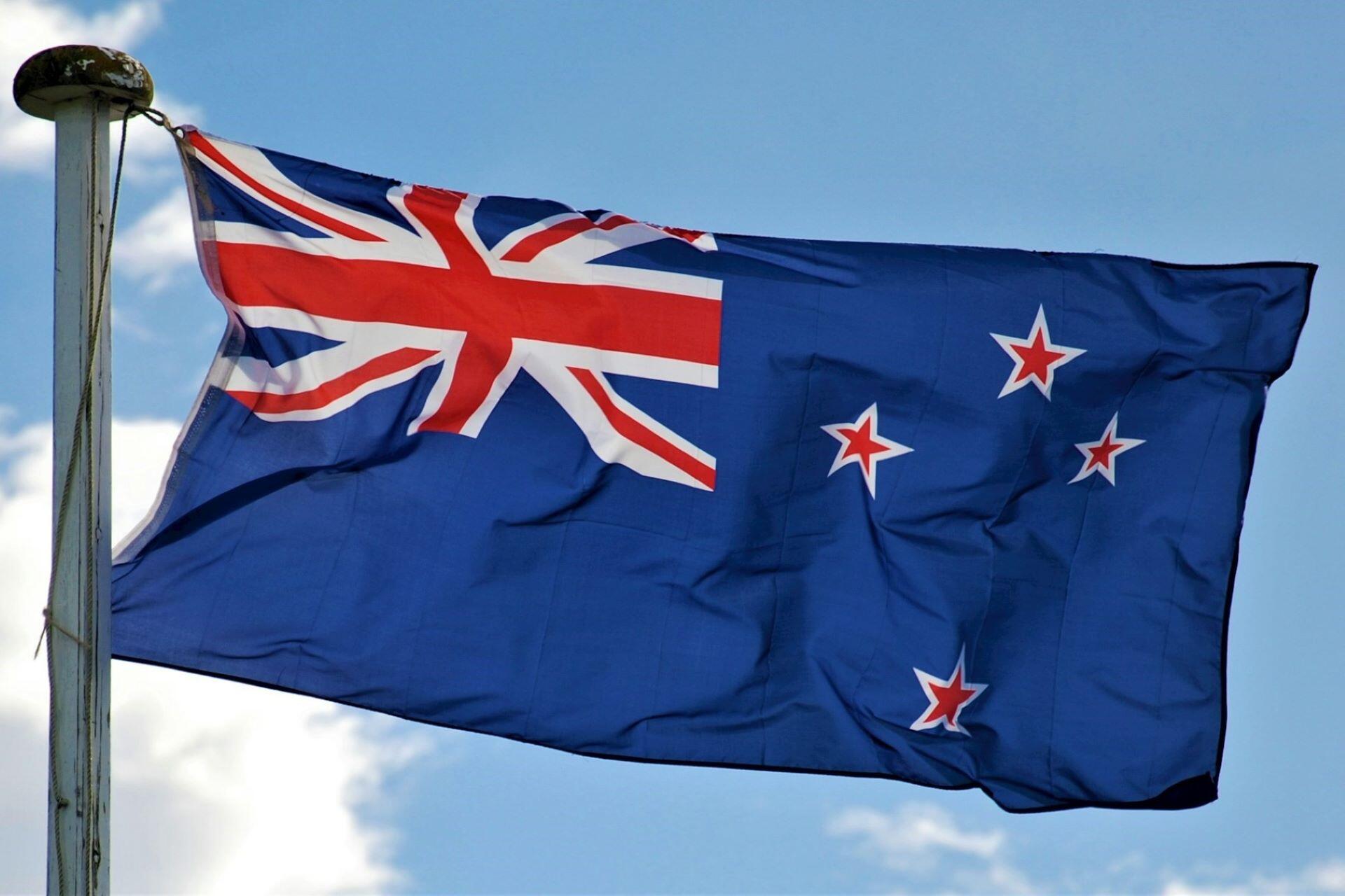 New Zealand flag flying from a flagpole against a blue sky