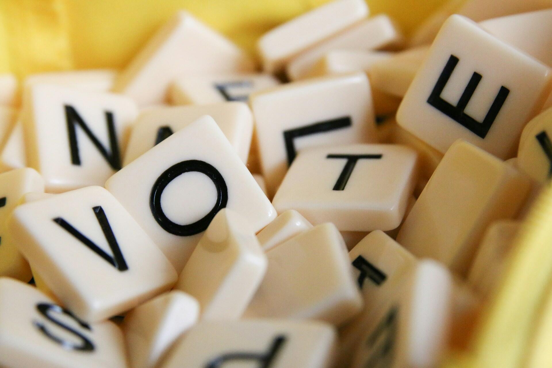 White letter tiles spelling VOTE among scattered tiles