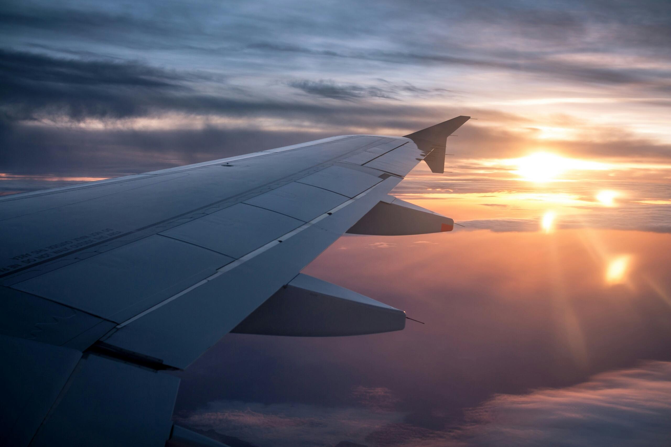 Vista del ala de un avión durante el atardecer, simbolizando los viajes de los aficionados para vivir la Champions League en diferentes países.