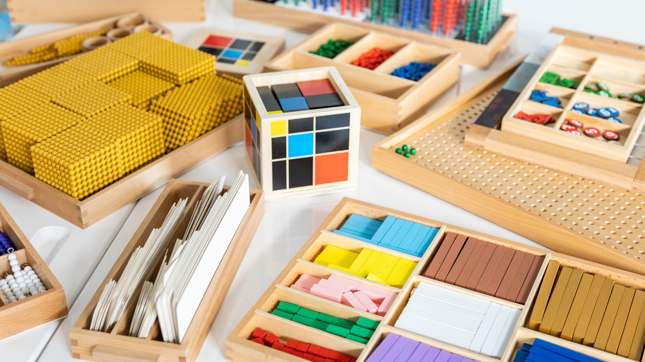 Materiales didácticos Montessori para la enseñanza de matemáticas, incluyendo bloques numéricos y fichas de colores.