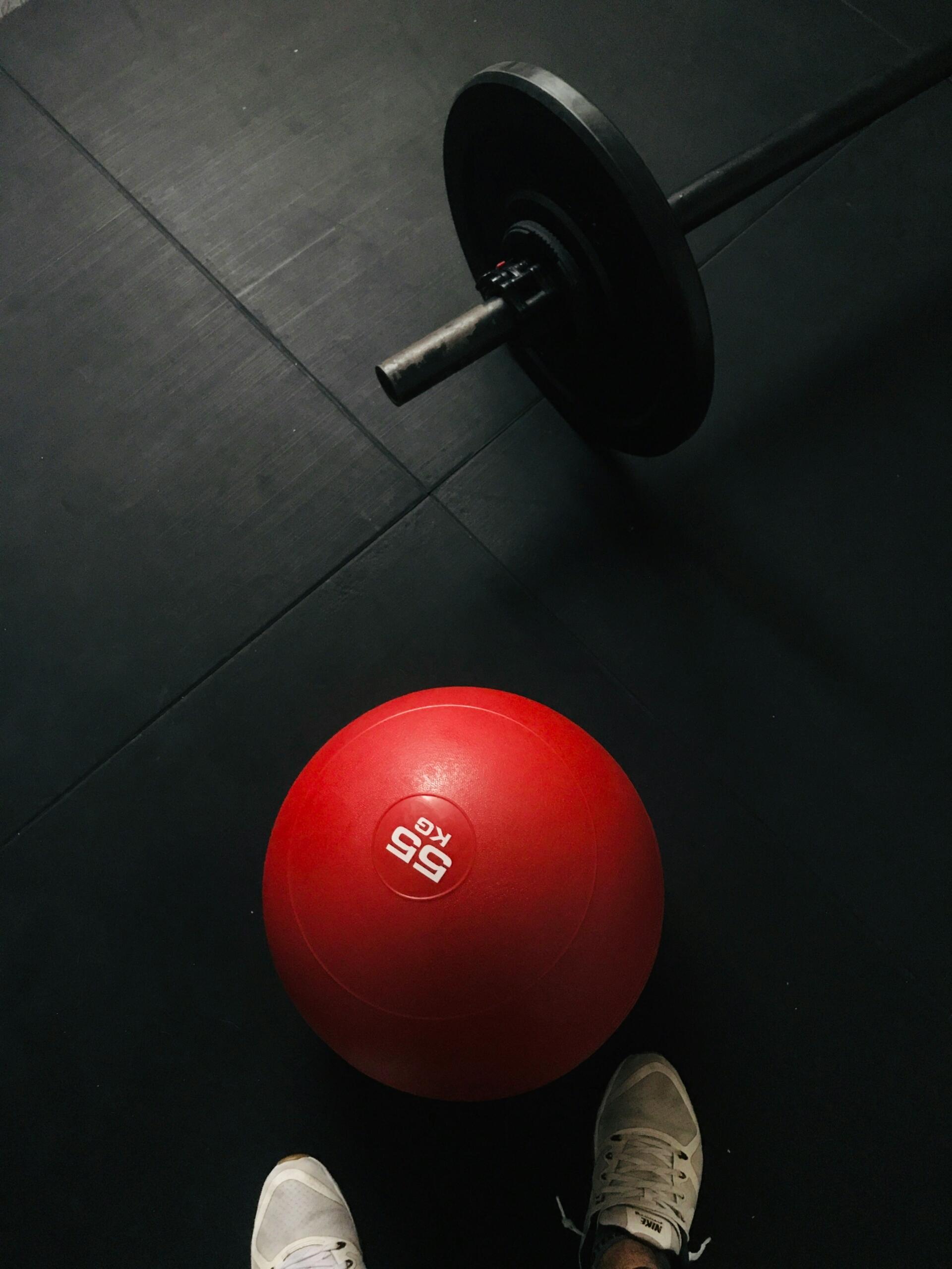 Pelota medicinal de 5 kg y barra de pesas listas para entrenamiento de fuerza.