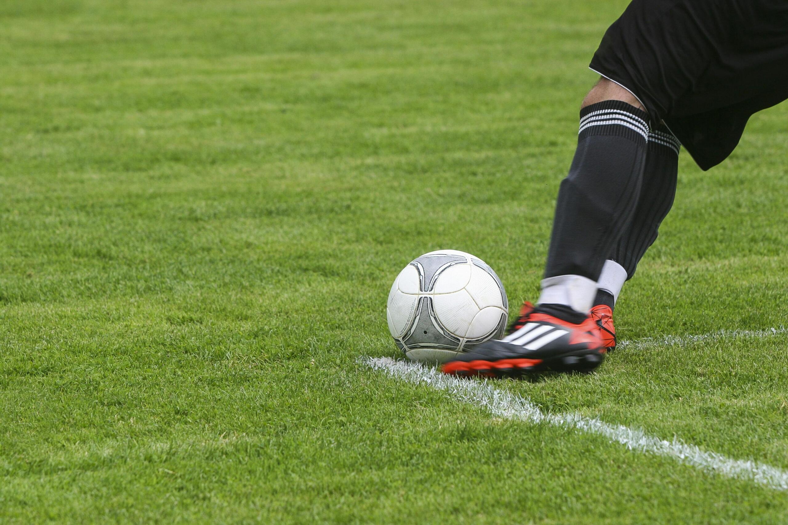 Jugador De Fútbol Pateando Una Pelota De Fútbol Gris Blanca En El Campo De Hierba Verde