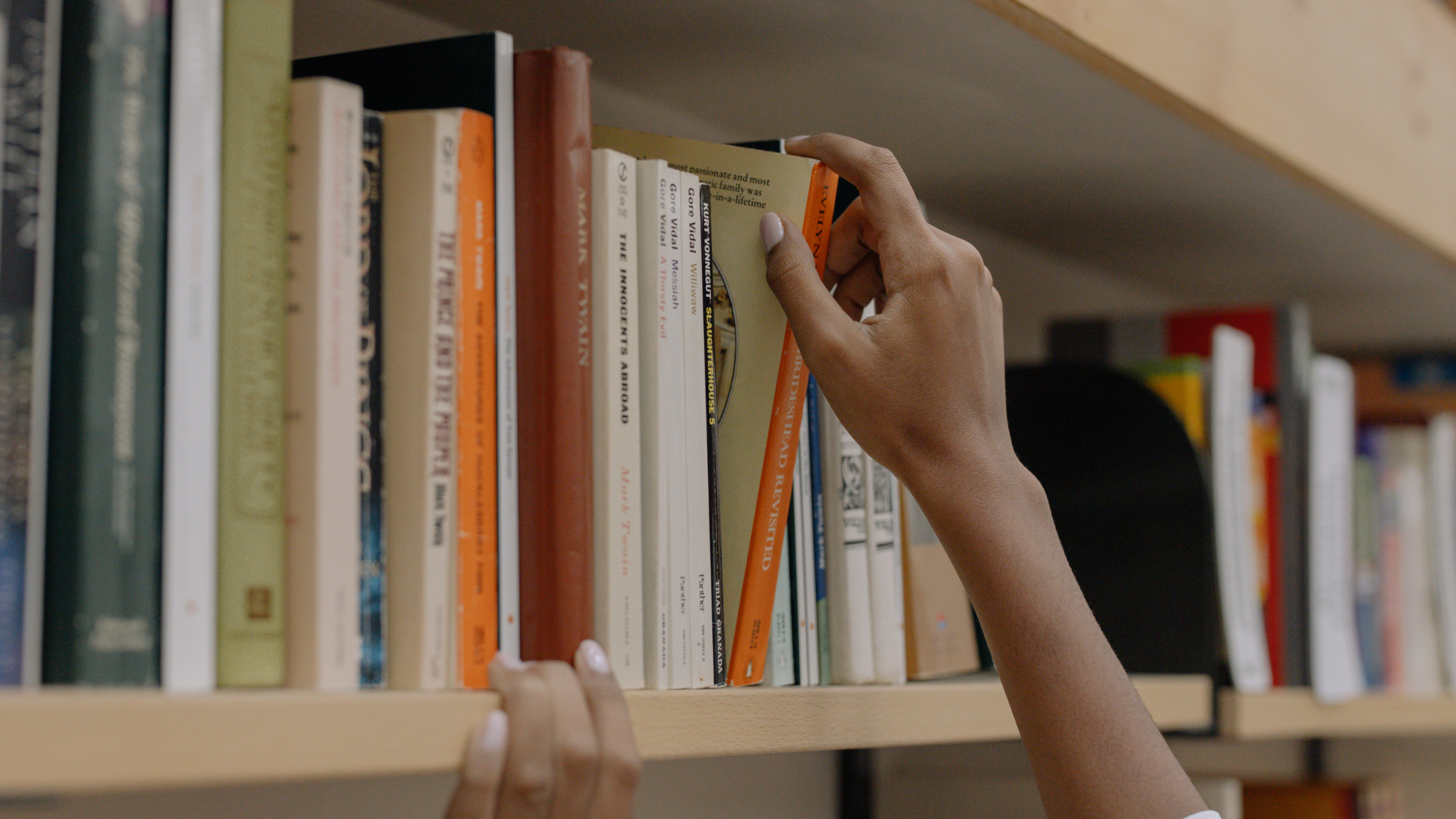 Persona eligiendo un libro en una biblioteca.