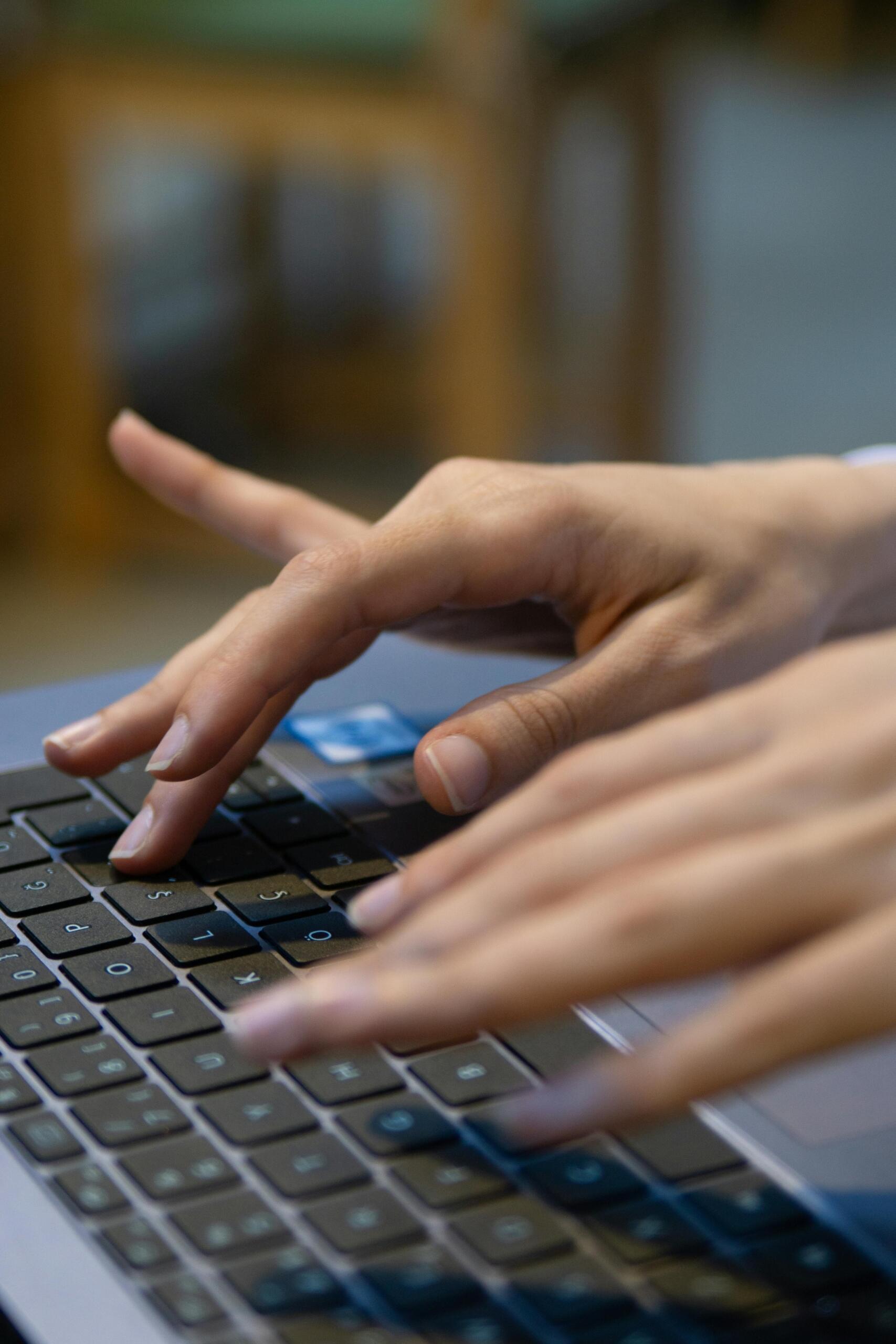 Manos escribiendo en teclado de computadora portátil durante sesión de trabajo o estudio.