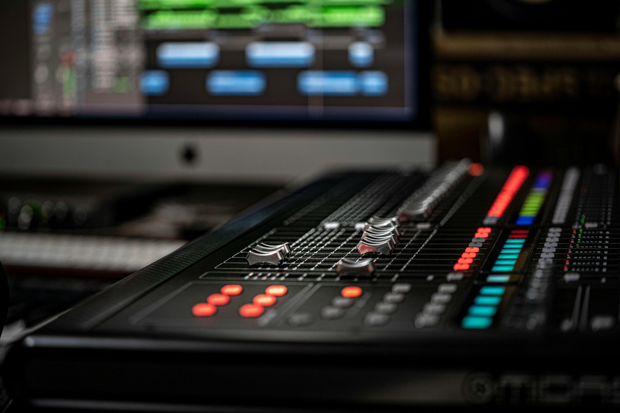 Primer plano de consola de sonido con controles deslizantes iluminados, equipo de mezcla en estudio de producción musical.