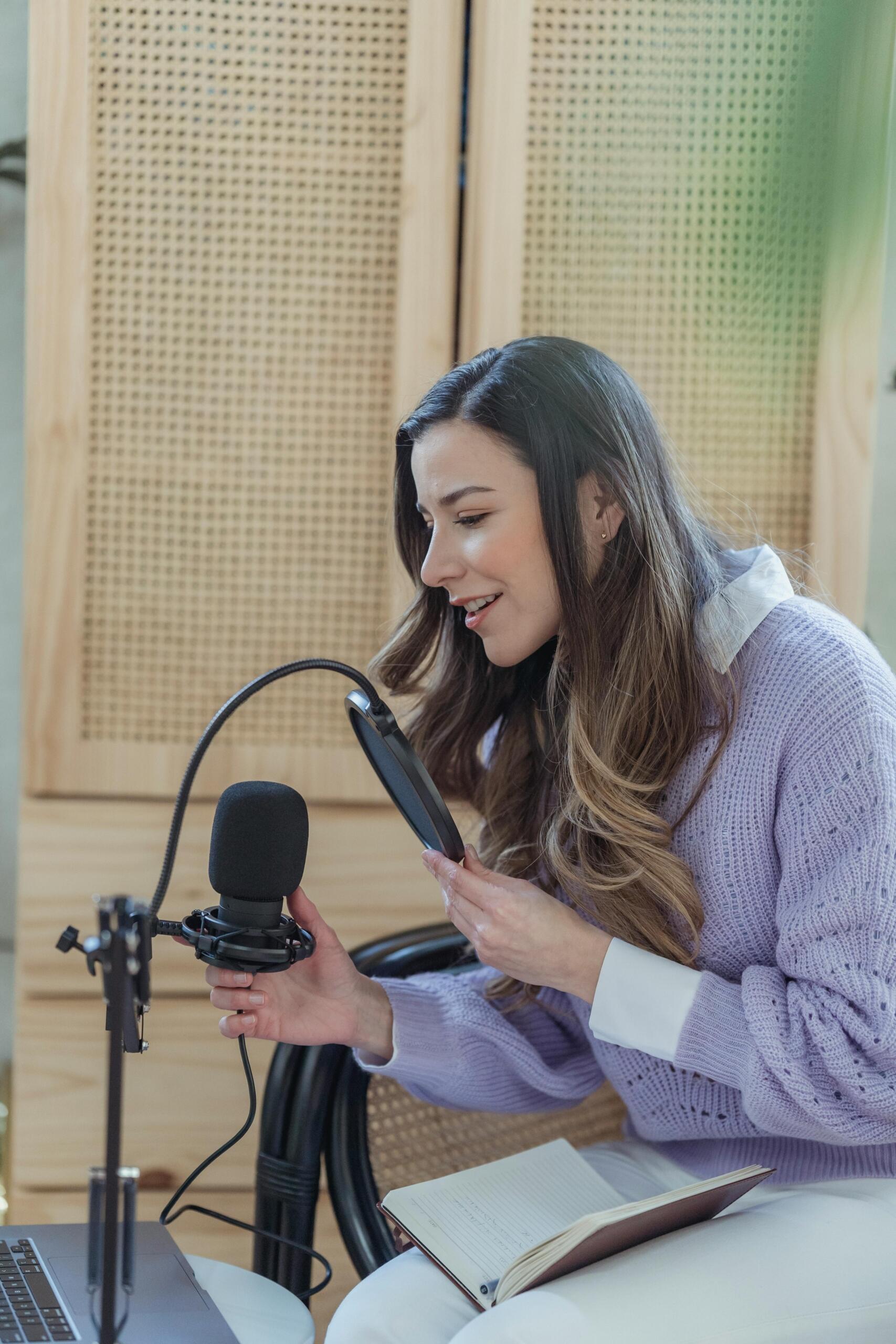 Mujer grabando contenido con micrófono en casa, participando en clase de canto virtual.
