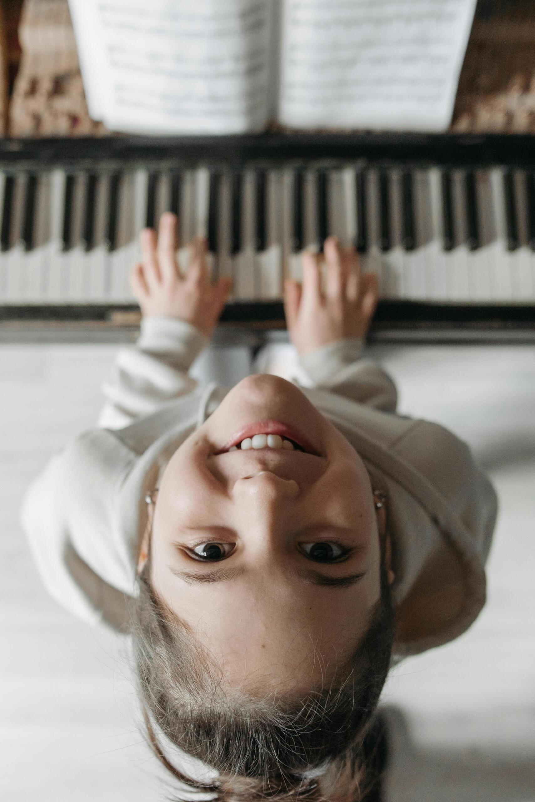 Vista Superior De Una Niña Mirando Hacia Arriba Mientras Toca El Piano