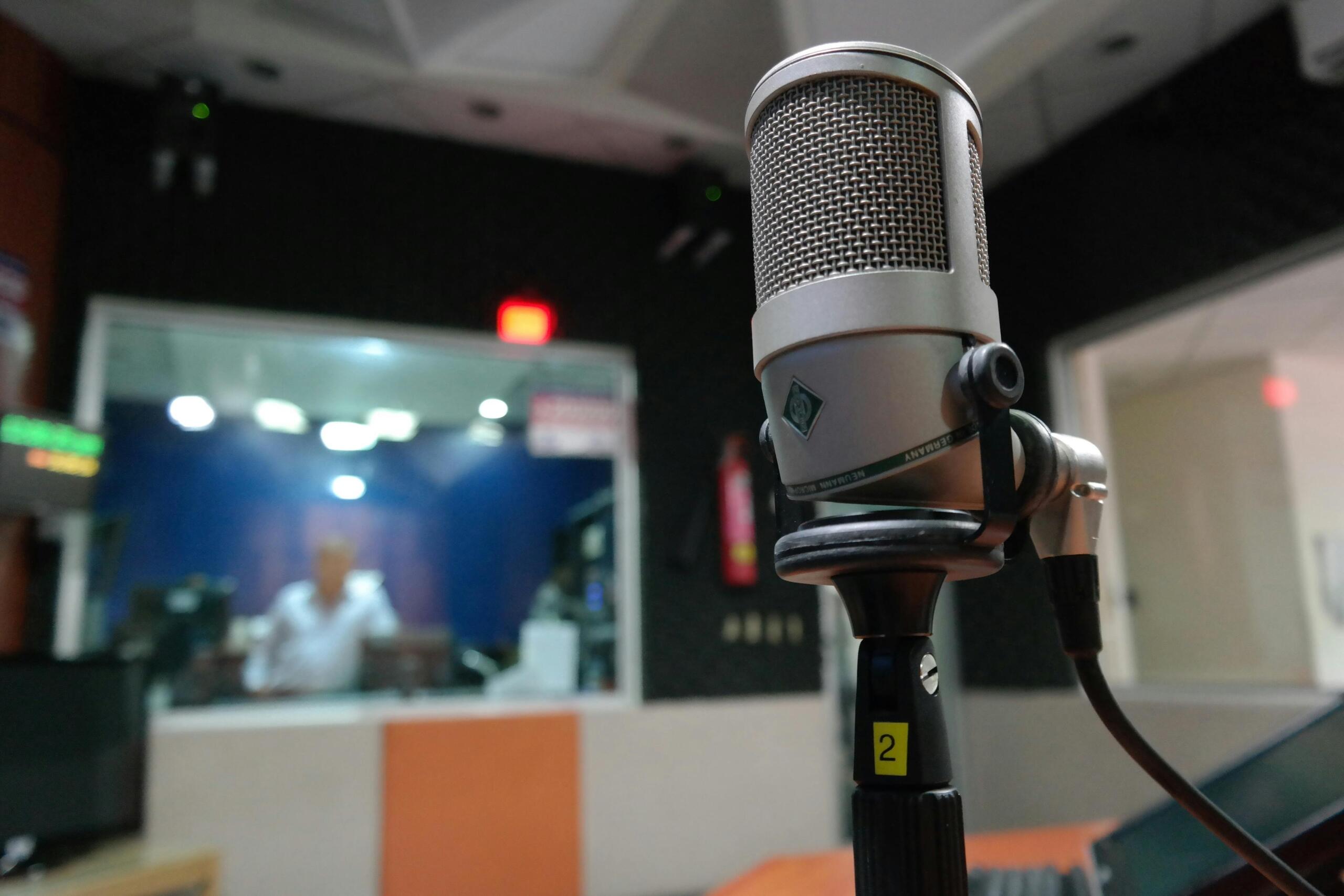 Micrófono de condensador en primer plano dentro de cabina de grabación, estudio de voz profesional con aislamiento acústico.