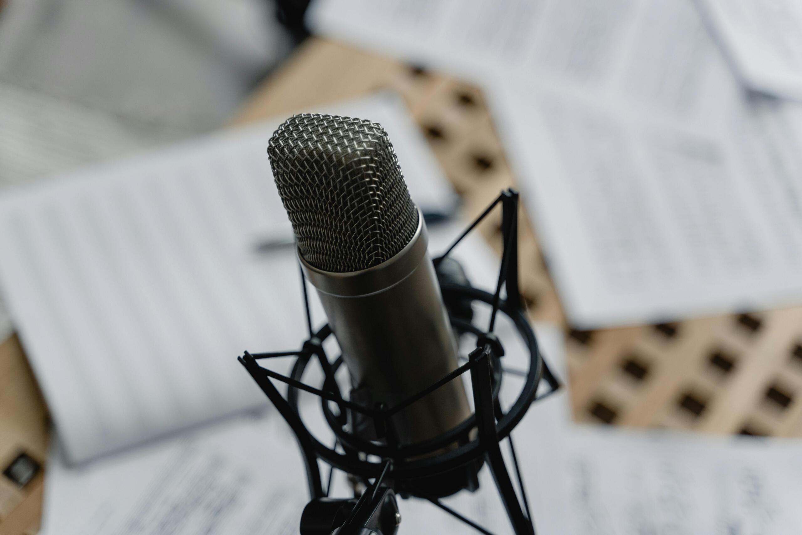 Micrófono de estudio profesional rodeado de partituras musicales, preparación para grabación vocal o composición.