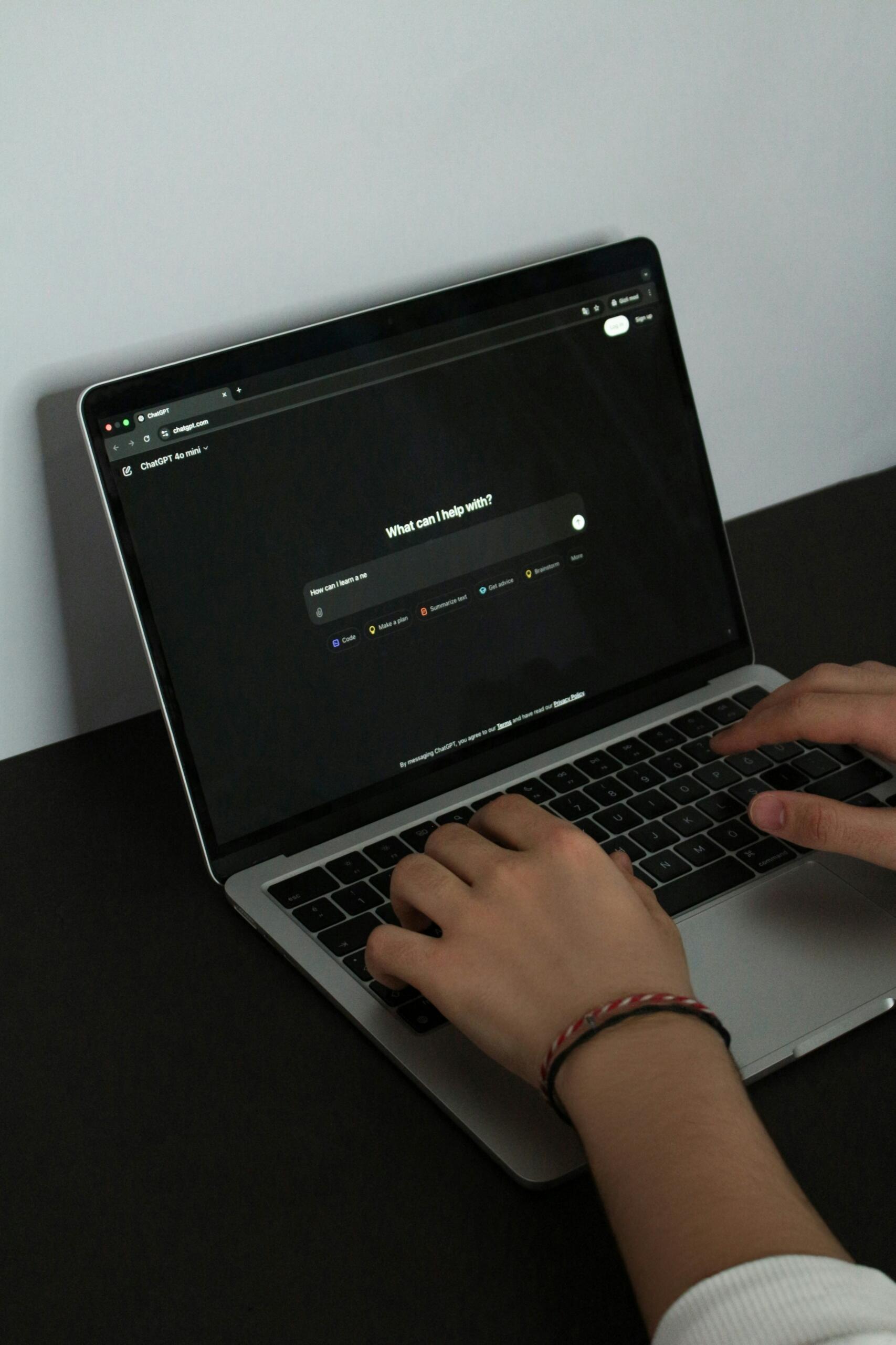 Manos escribiendo en laptop con interfaz de asistente digital.