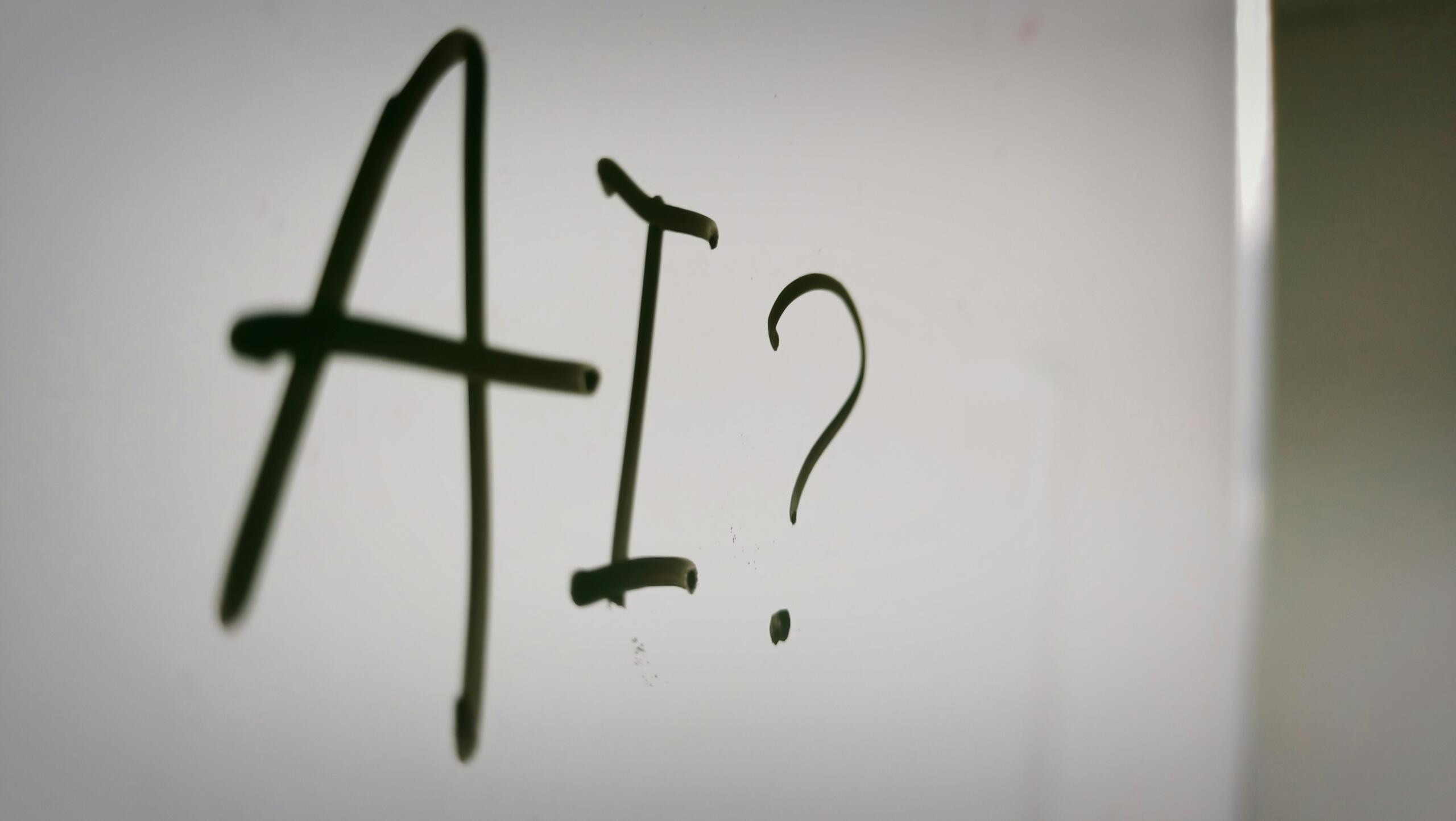 Texto 'AI?' escrito en una superficie blanca.