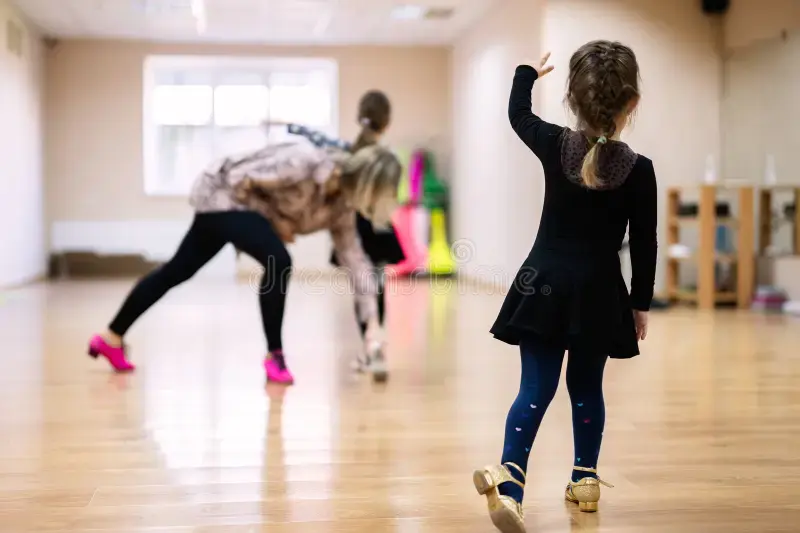 Niña aprendiendo a bailar en el aula con la guía del instructor