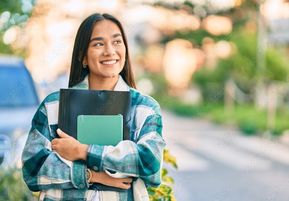 Joven estudiante latina sonriendo feliz carpeta en la ciudad.