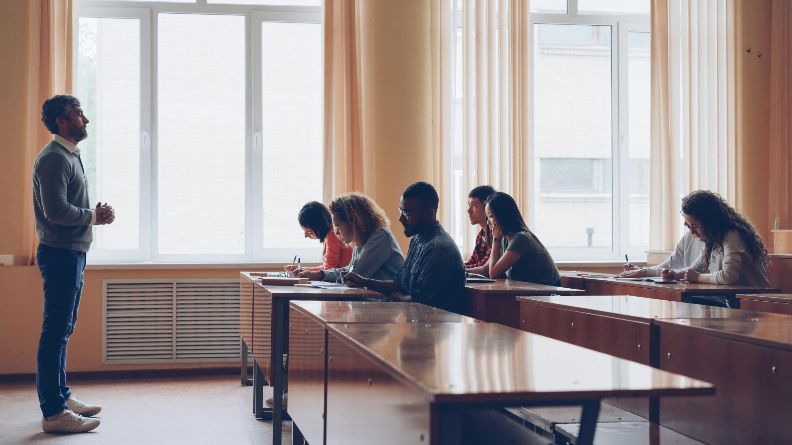 Profesor dando clases presenciales a un grupo de estudiantes en un aula luminosa en Panamá.