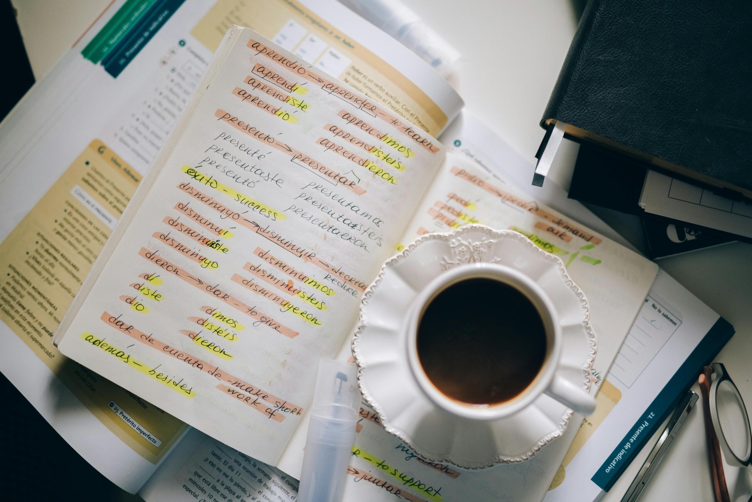 Cuaderno de estudio con vocabulario en español resaltado y taza de café durante una sesión de aprendizaje.