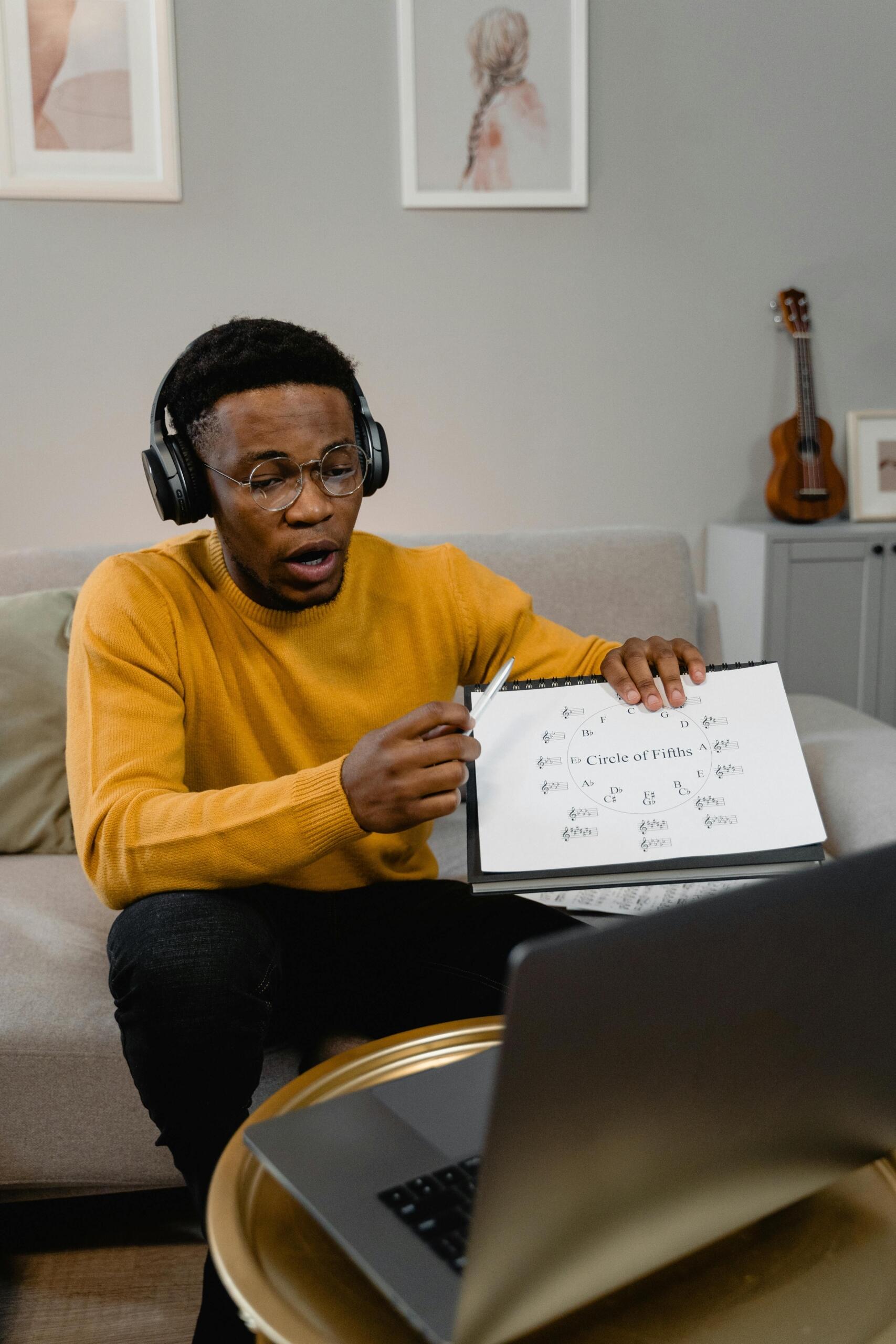 Profesor de música dando una clase de piano online, explicando el círculo de quintas frente a una computadora portátil.