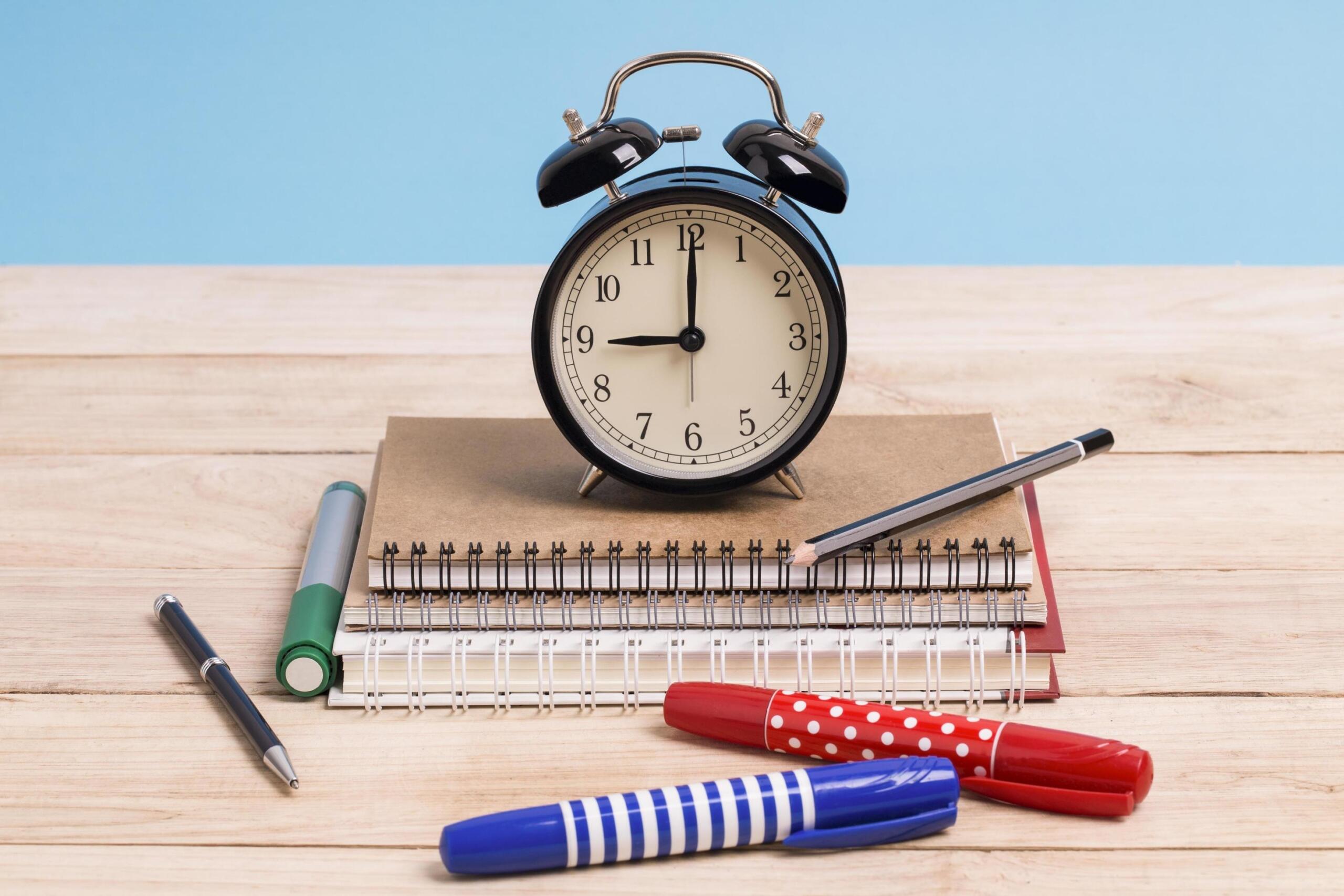 clock-on-notebooks-with-writing-utensils-free-photo