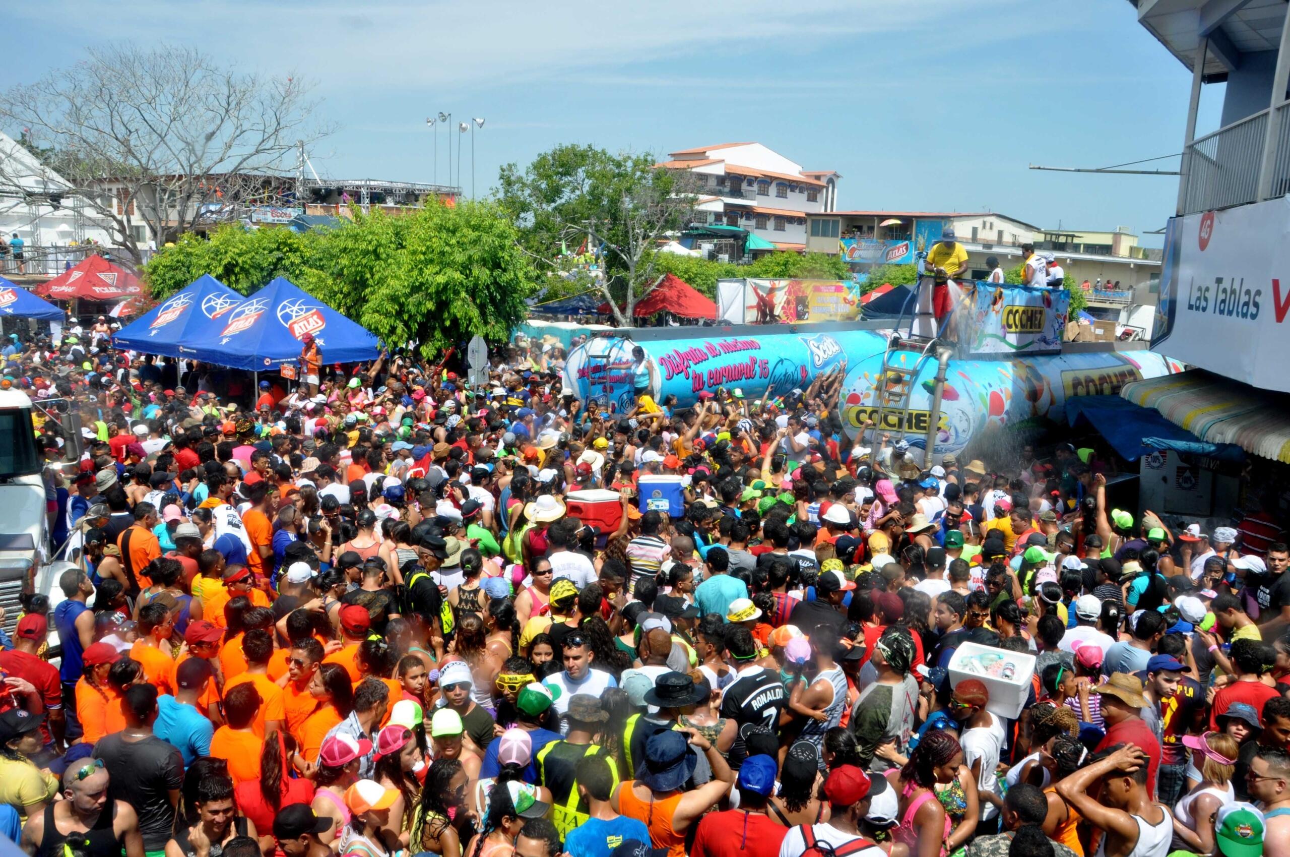 Culeco masivo en Las Tablas con camiones cisterna rociando agua sobre multitud colorida.