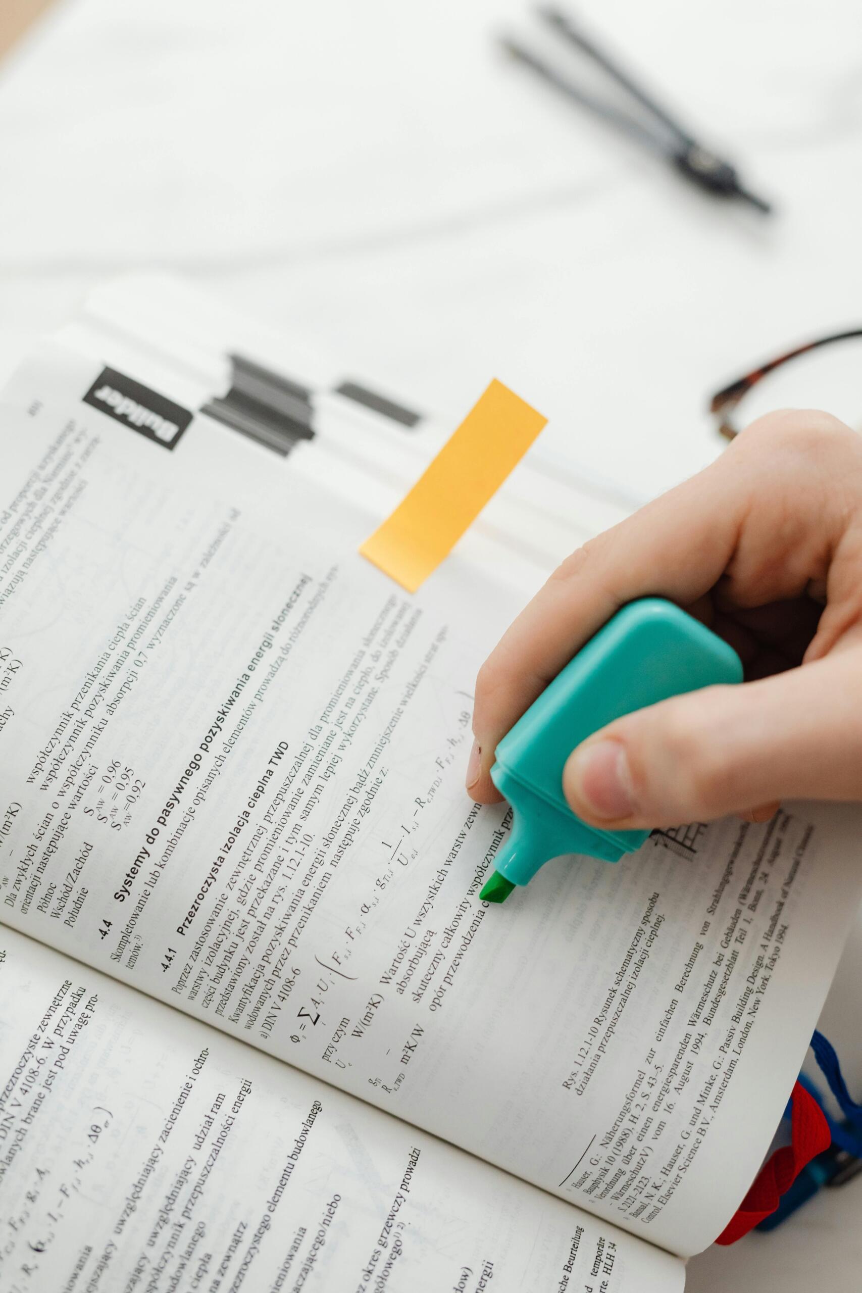 Estudiante subrayando con marcador verde fórmulas matemáticas y de física en libro académico, durante sesión de estudio con apuntes y materiales de apoyo.