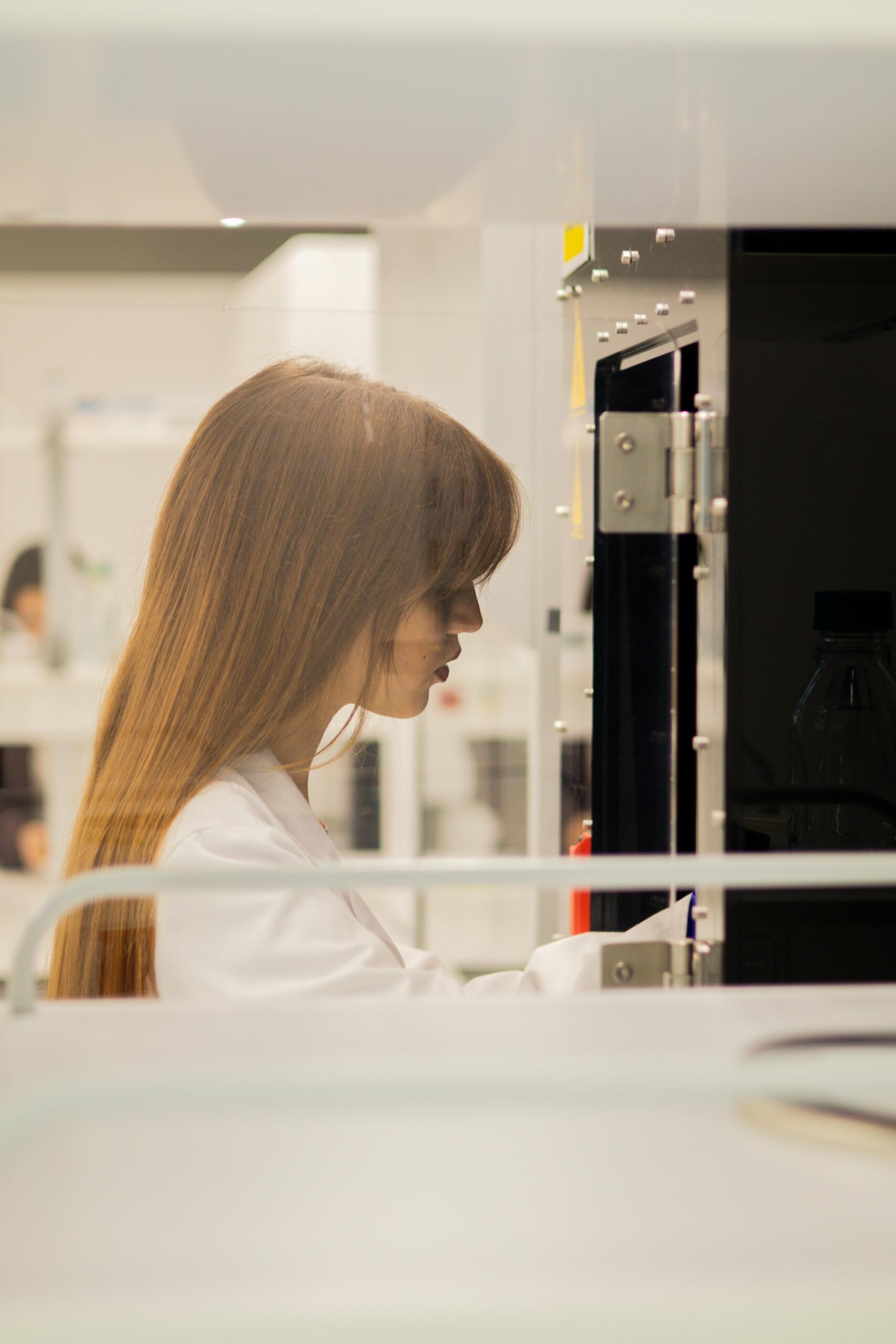 Estudiante de biología con bata blanca trabajando en un laboratorio universitario.