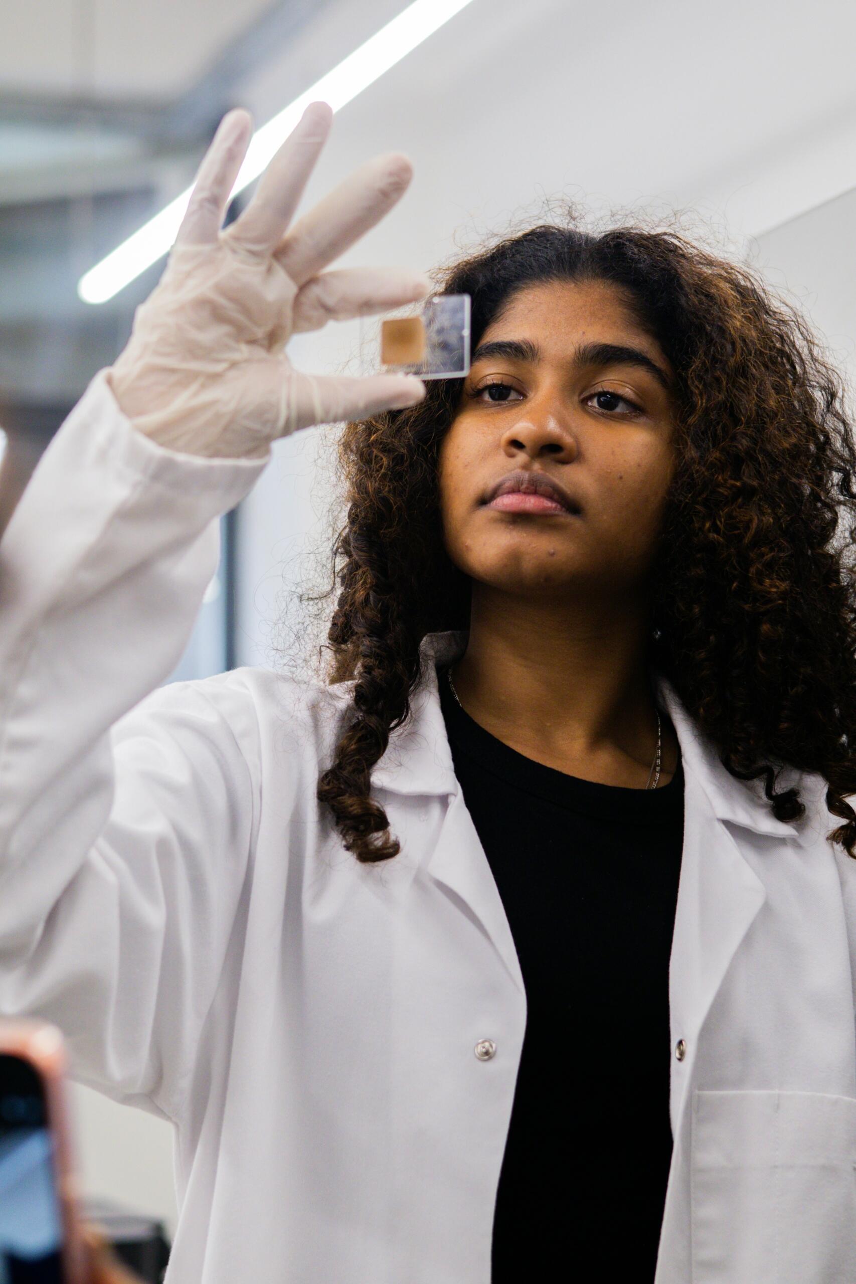 Joven científica observando una muestra en un portaobjetos en el laboratorio.
