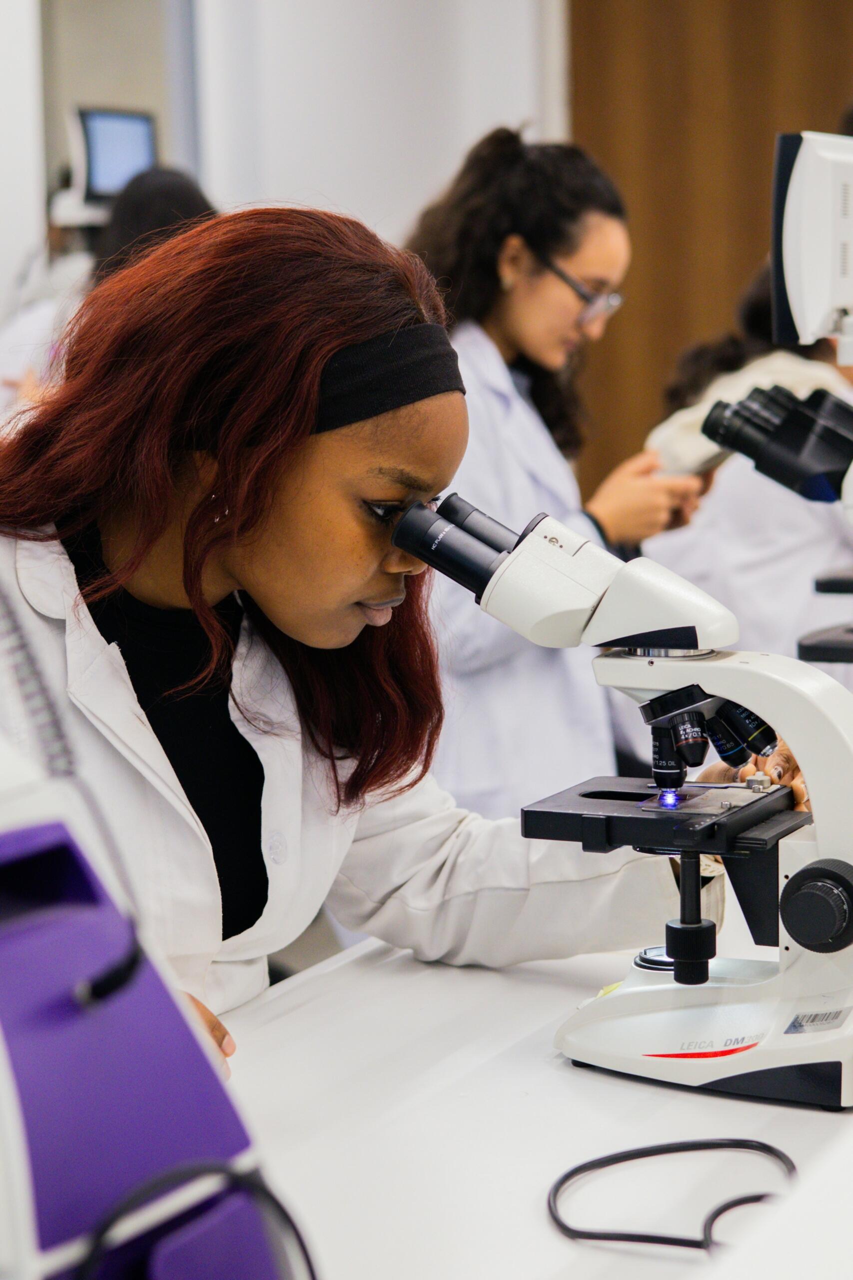Estudiante de biología observando una muestra por el microscopio en clase de laboratorio.